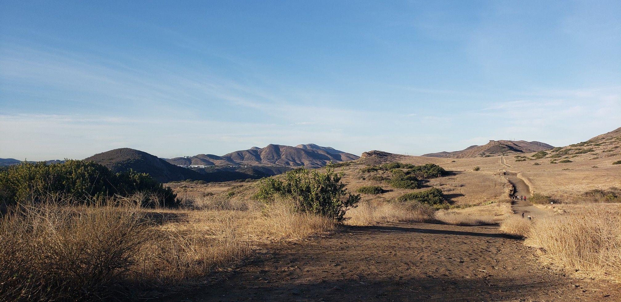 Wide view of dry, rolling hills with a dirt path and distant mountains under blue sky. - Santa Rosa Trail and Lower Butte Trail Loop