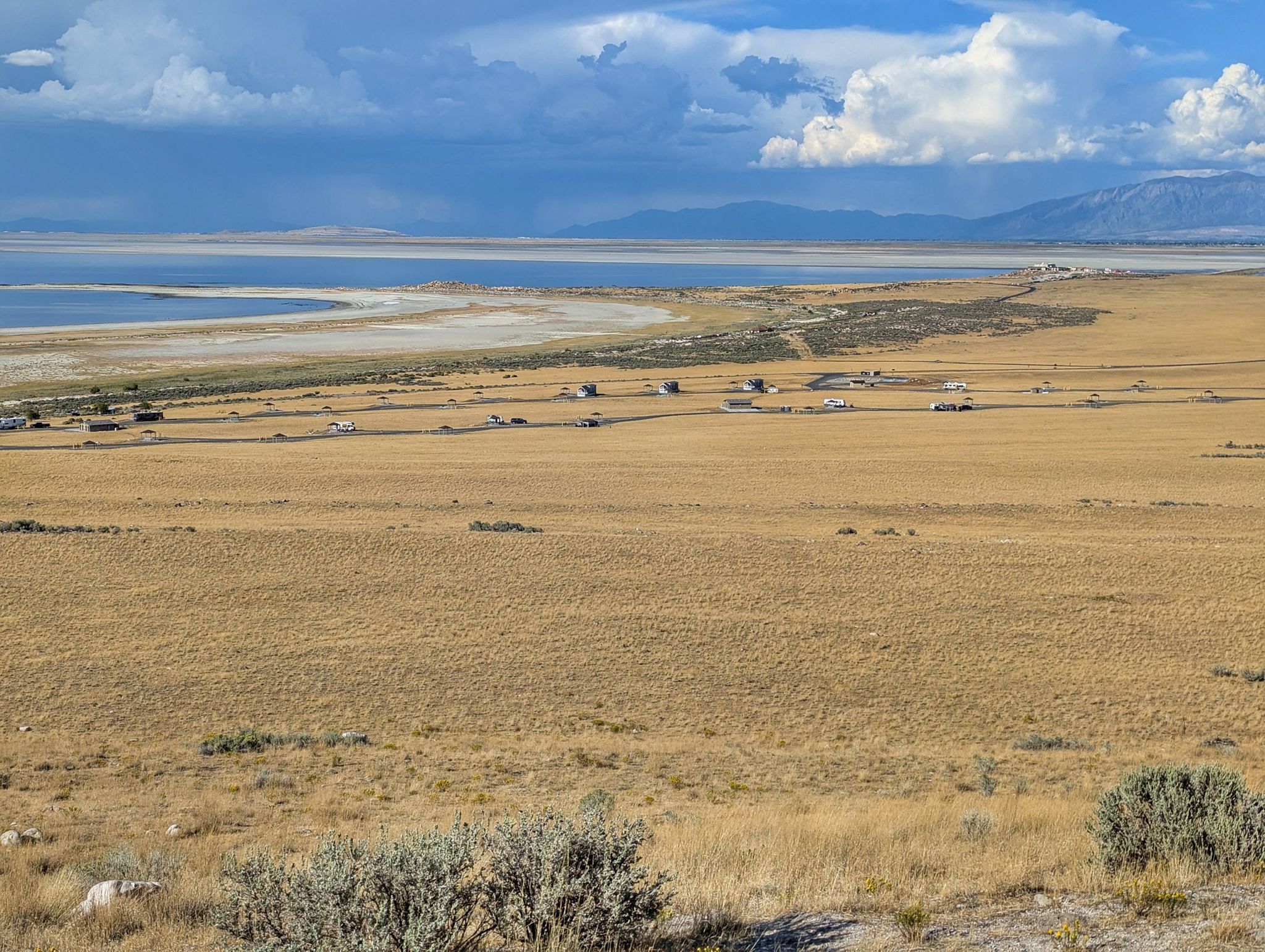 Wide view of dry fields, a large lake, and distant mountains under cloudy skies. - Buffalo Point Trailhead – Buffalo Point loop from Buffalo Point