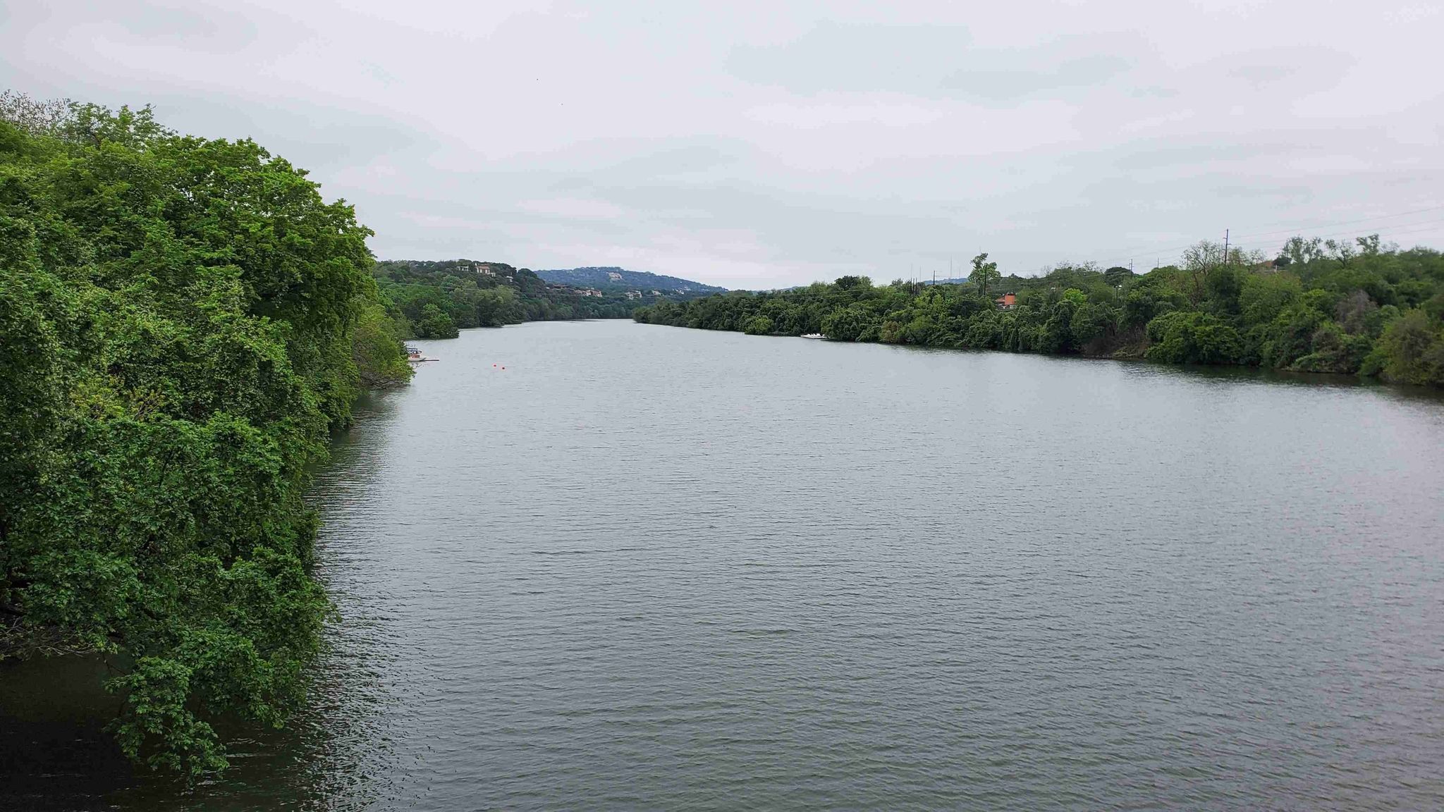 Wide river flowing between lush green banks under an overcast sky. - Winding Path in Zilker Park – Lou Neff Point loop from Crestview