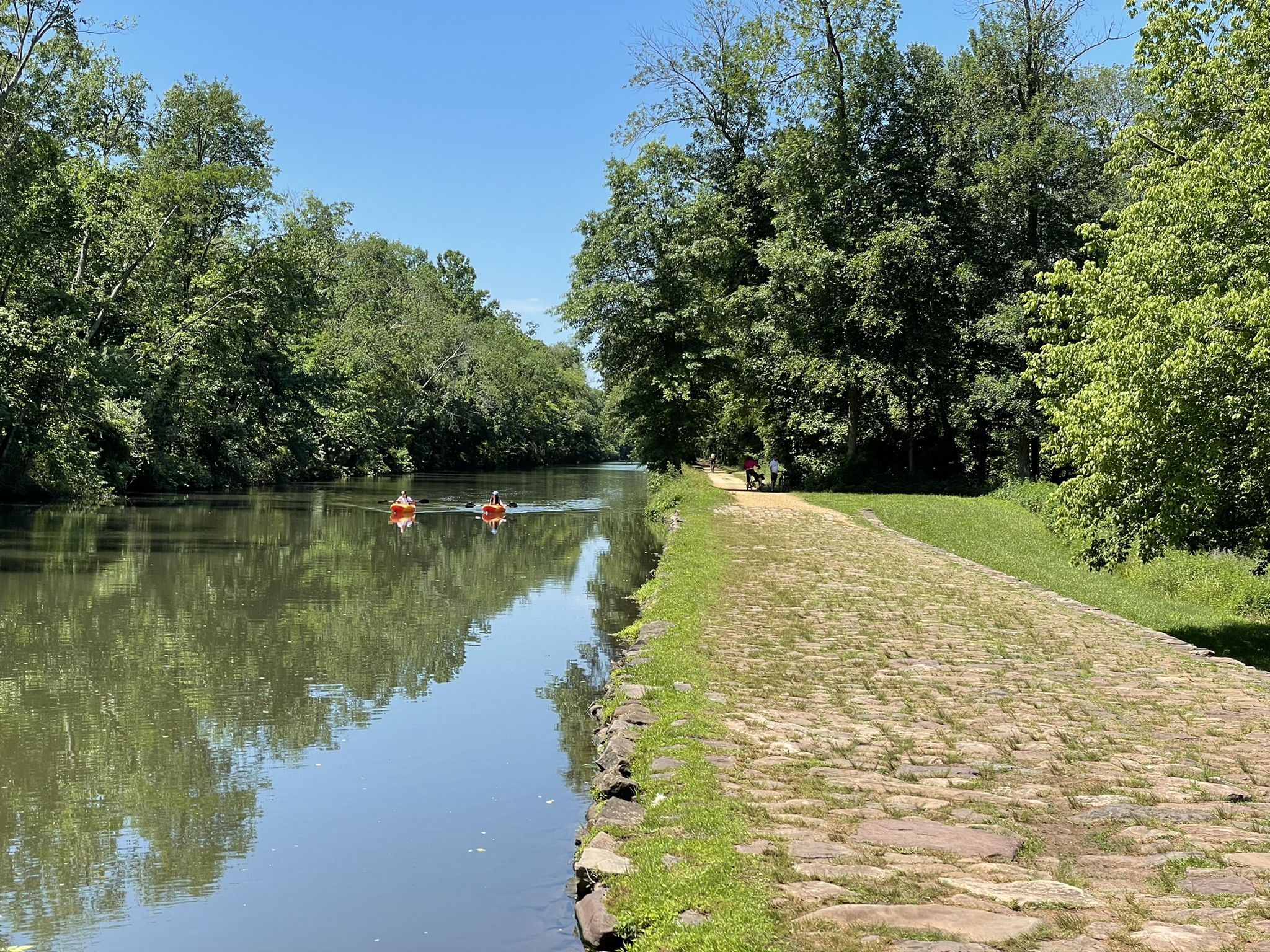 Two people kayak on a calm canal lined with green trees. - Challenging Downhill Twist – Red Trail loop from Rocky Hill