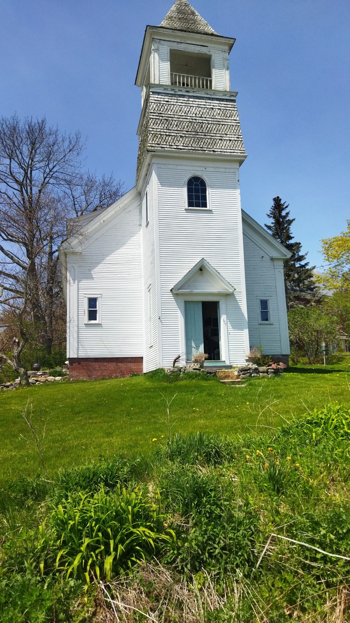 White wooden church with a tall steeple on a sunny grassy hill. - Coastal Rivers Conservation Trust & Twin Villages loop from Waldoboro, Maine