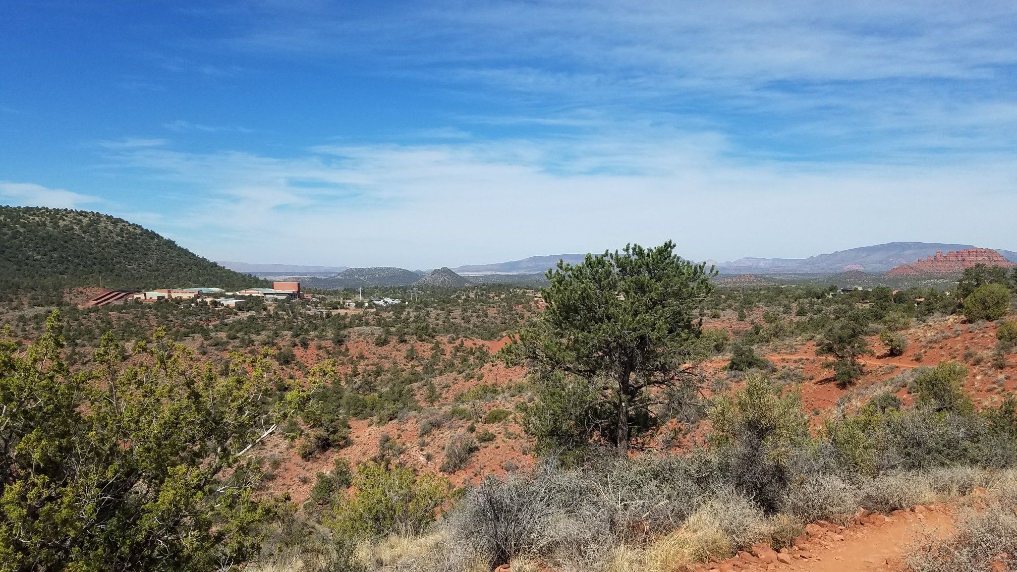 Wide desert landscape with green shrubs, distant buildings, and bright blue sky. - Skywalker, Old Post, and Herkenham Loop