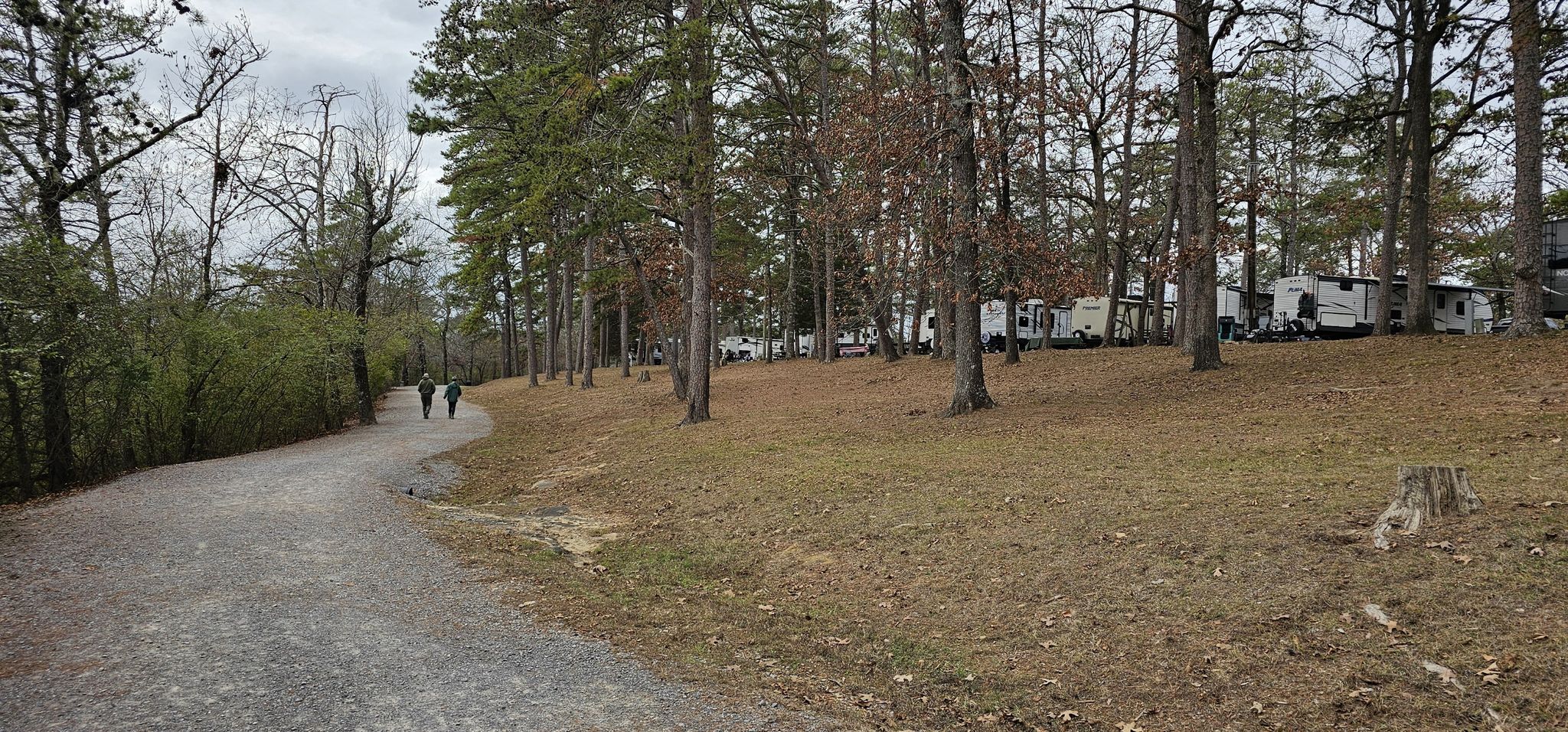 Two people walk on a dirt path through a wooded area with RVs. - Whatley Trail, Drift Mine, and Black Creek Trail
