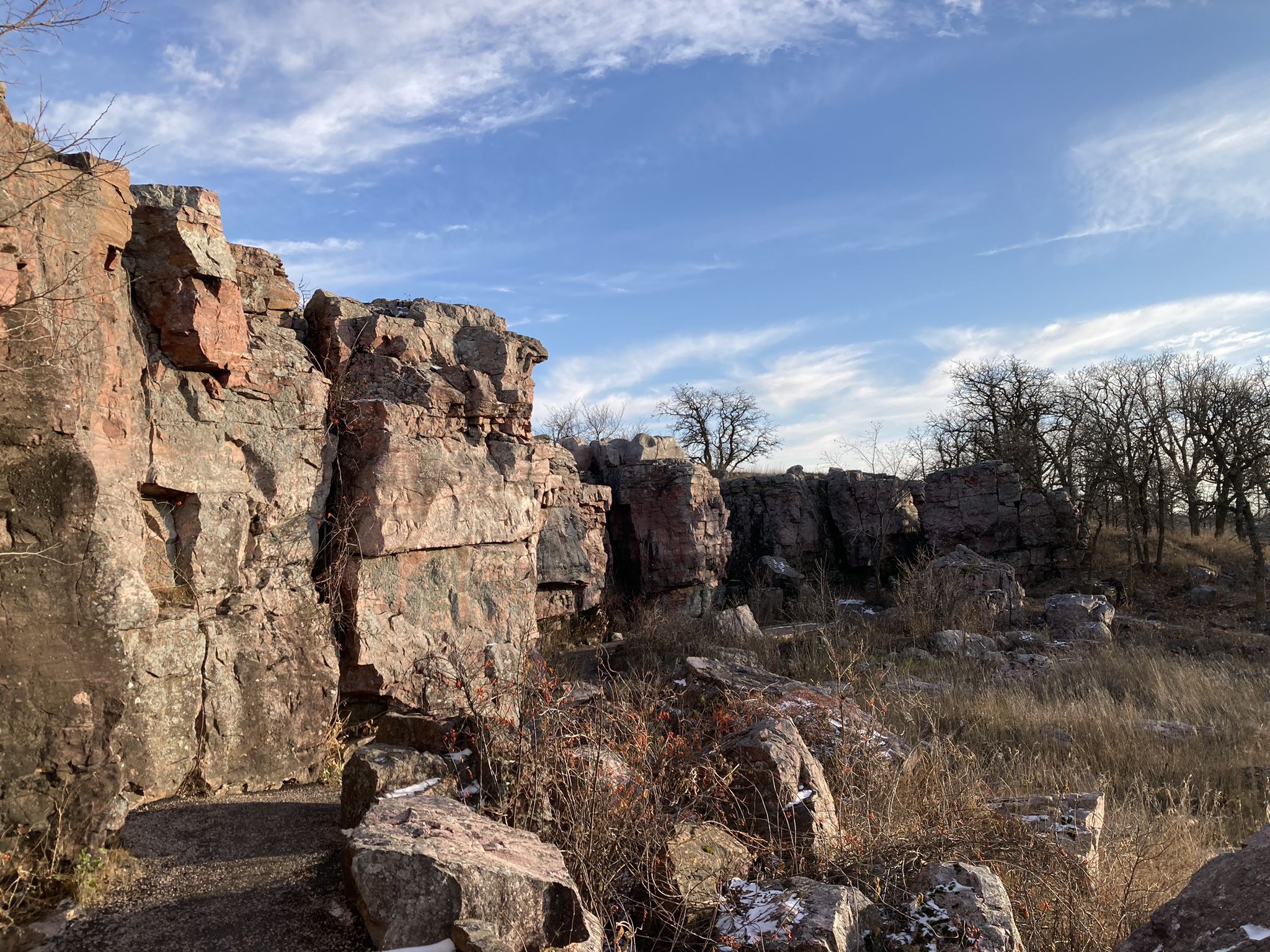 Large red rock formations under a bright blue sky with dry grass. - Circle Trail