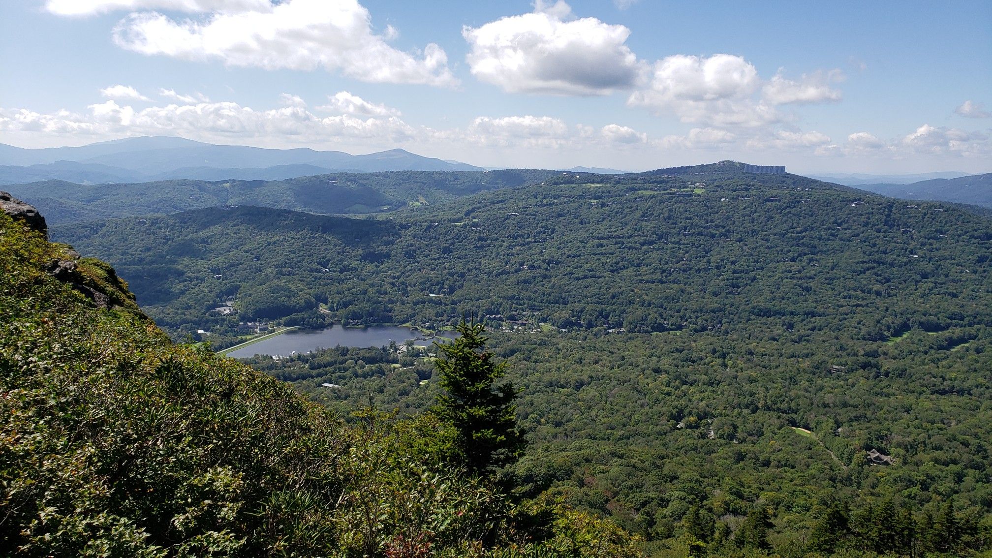 Panoramic view of a forested mountain landscape with a lake under a cloudy sky. - Grandfather and Underwood Trail Loop