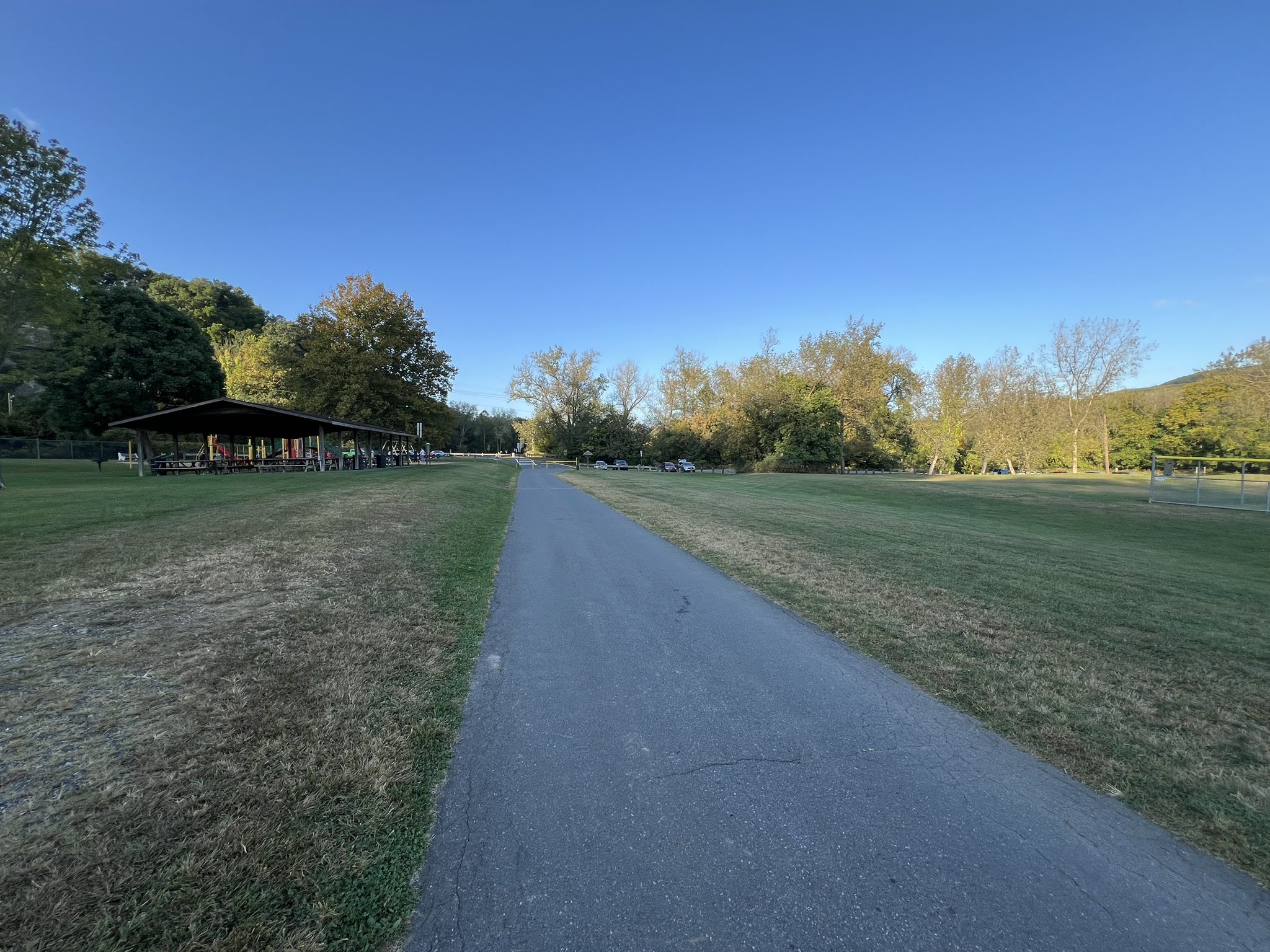 A paved path leads through grassy fields towards a distant shelter. - Two Rivers Trailway — Palmer loop from Old Orchard
