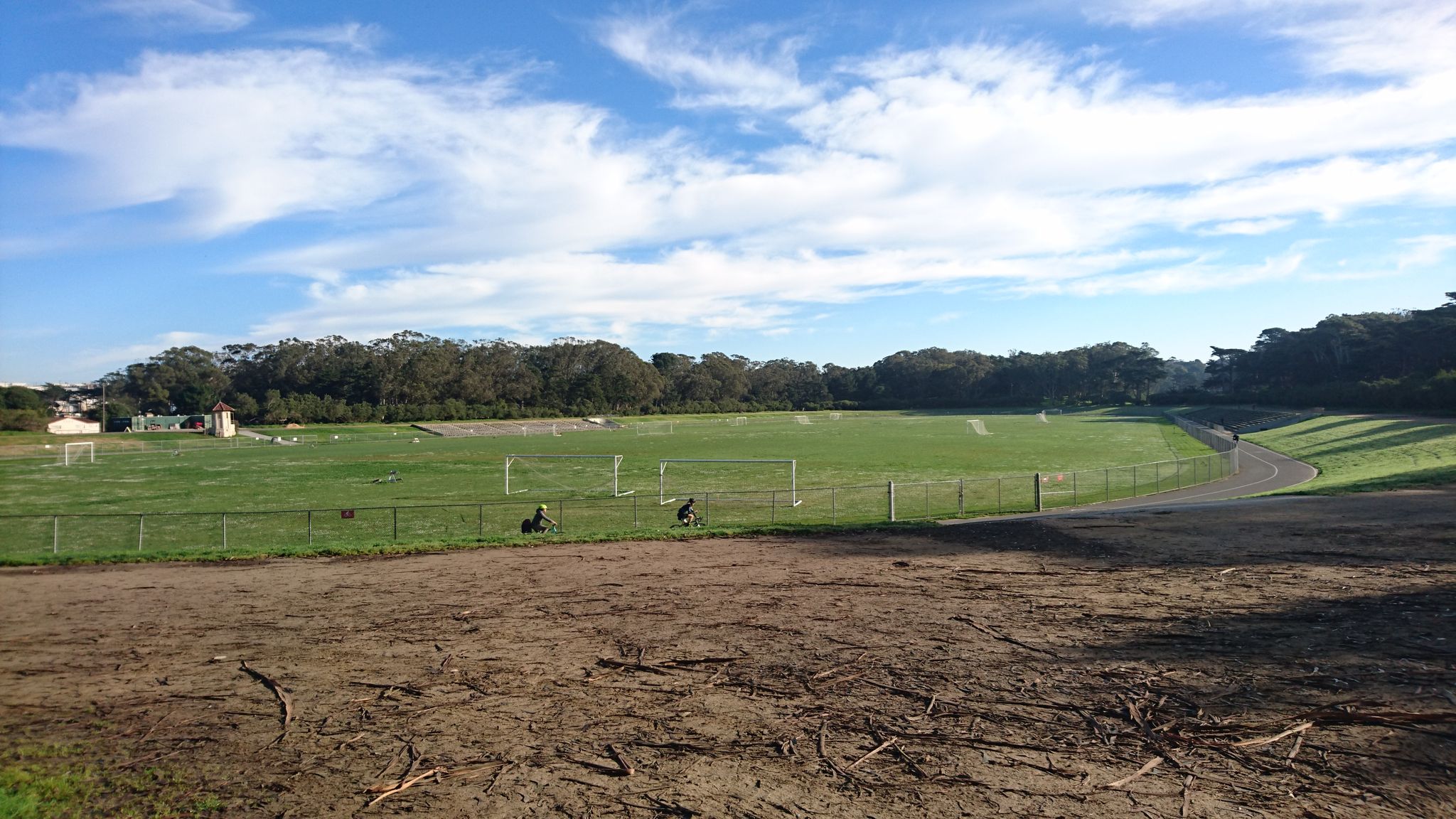 Wide green sports field with distant trees under a bright blue sky. - Golden Gate Park loop