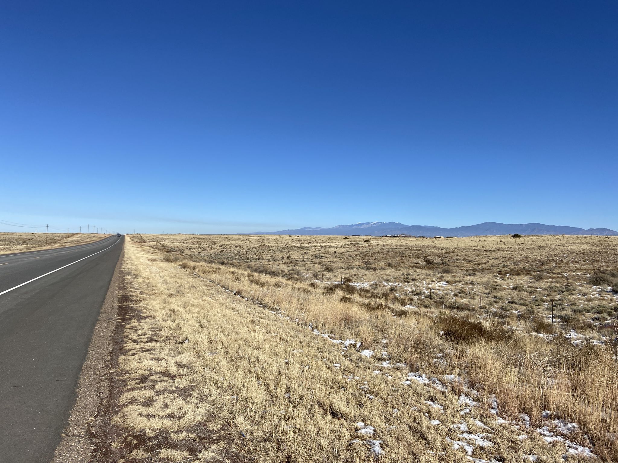 A long, straight road through a vast, arid plain with distant mountains. - El Rancho de las Golondrinas loop from Agua Fria