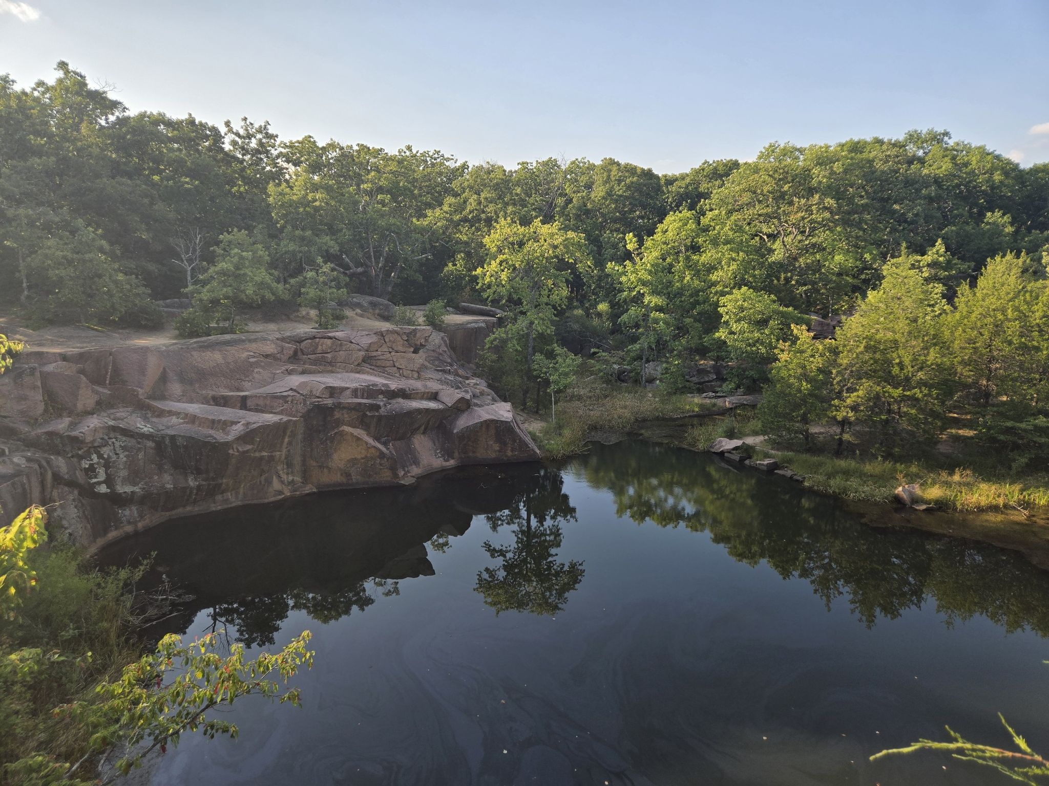Dark pond reflecting trees, surrounded by rocky cliffs and lush green forest. - Elephant Rocks loop from Elephant Rocks State Park