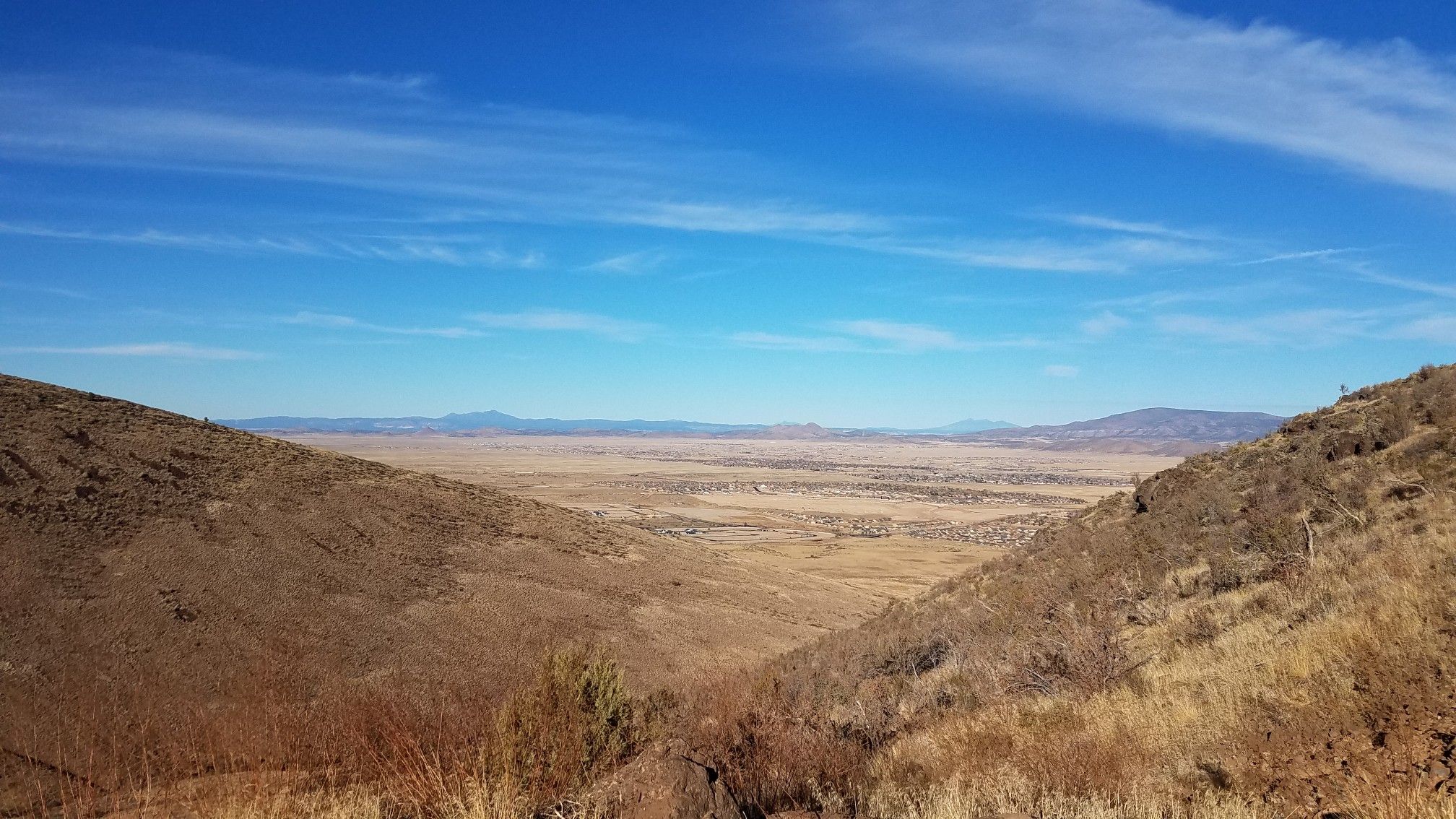 Wide valley between dry, rocky hillsides under a bright blue sky. - Glassford Summit Trail