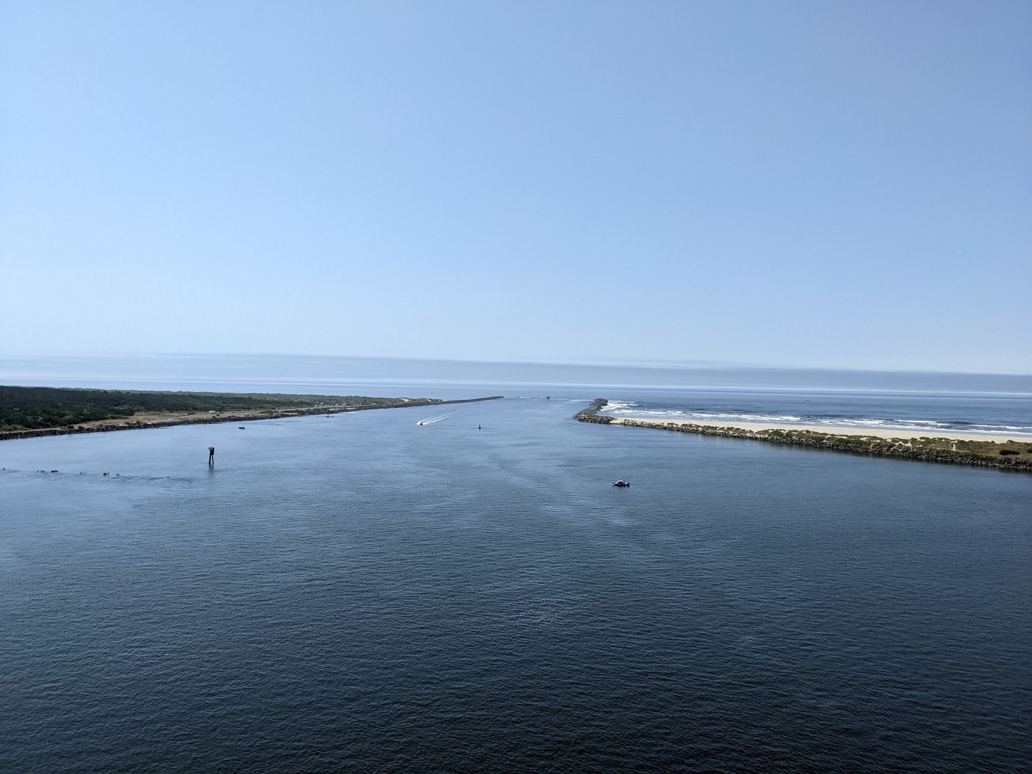 Expansive blue water meets the ocean, with distant land under clear sky. - Yaquina River loop