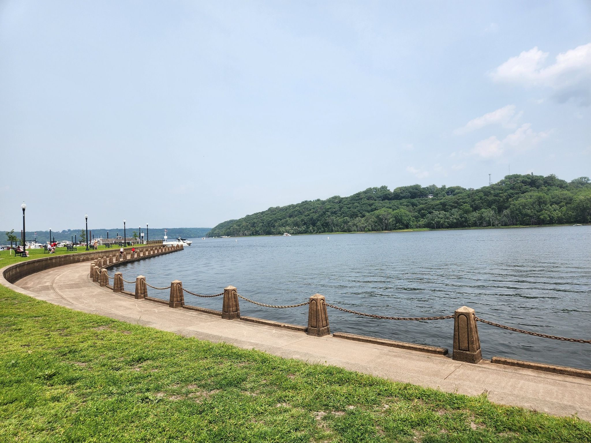 Paved path curving along a wide river with a distant green hill. - Picnic Area – Boom Site Cave loop from Stillwater