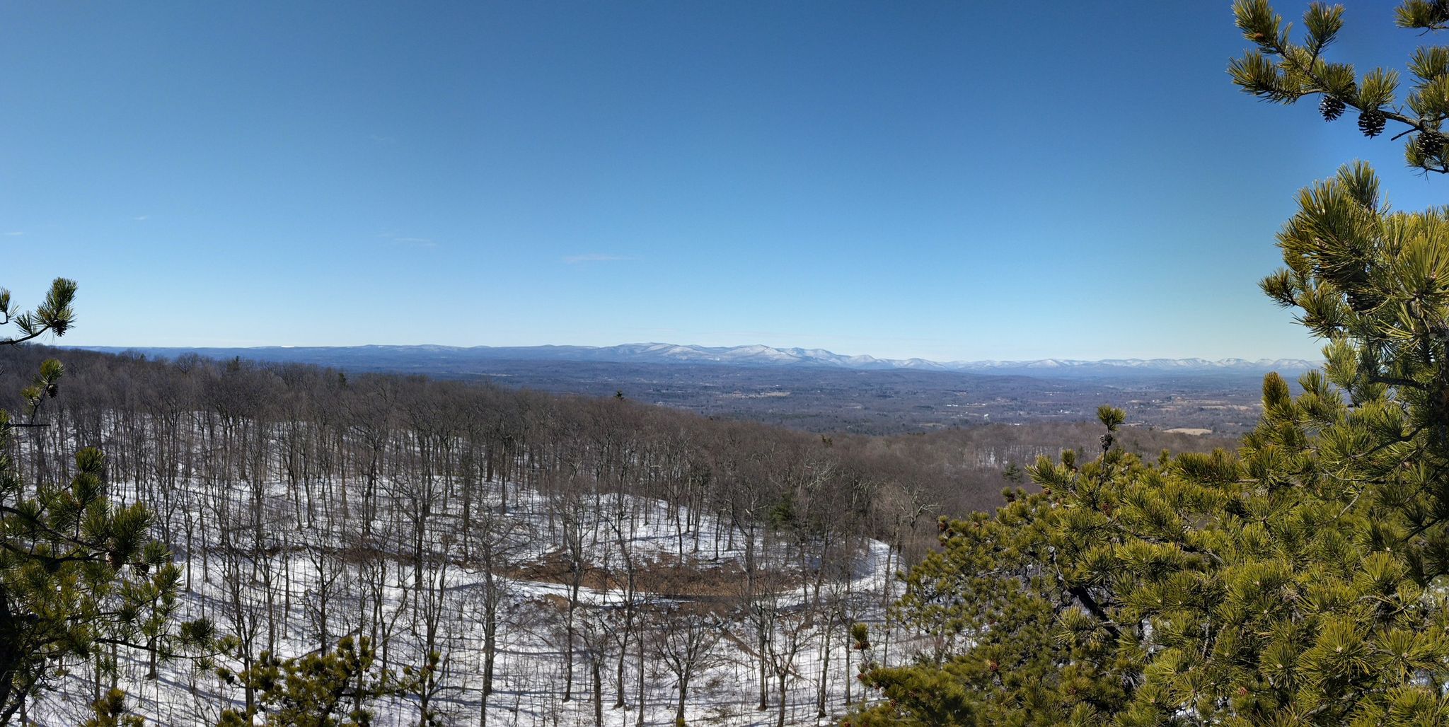 Panoramic view of a snowy forest valley and distant mountains under clear sky. - Bonticou Crag Trail