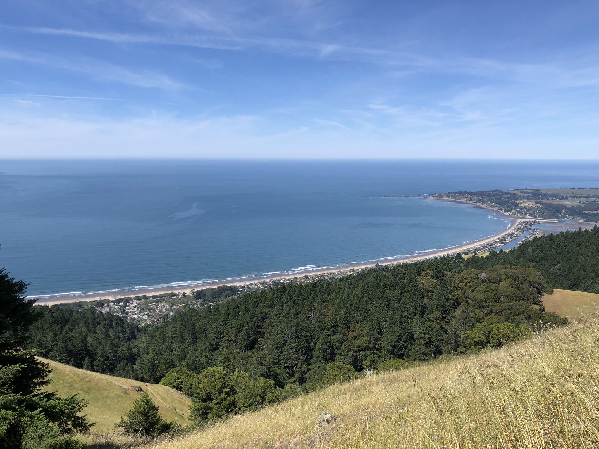 Aerial view of a long sandy beach, ocean, and forested hills under clear sky. - Alpine Dam Loop from San Francisco