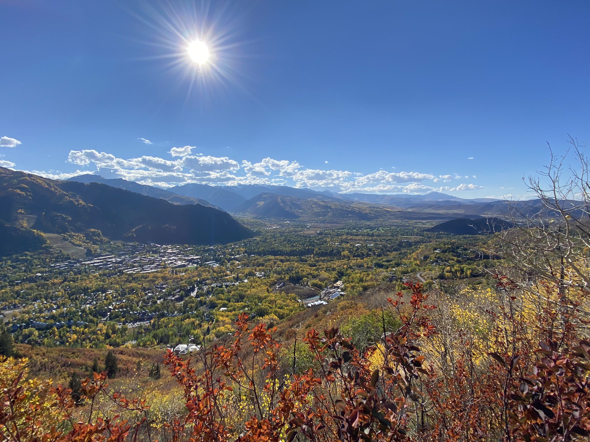 Panoramic view of a valley town and mountains under a bright sunny sky. - Follow the Creek loop from Aspen