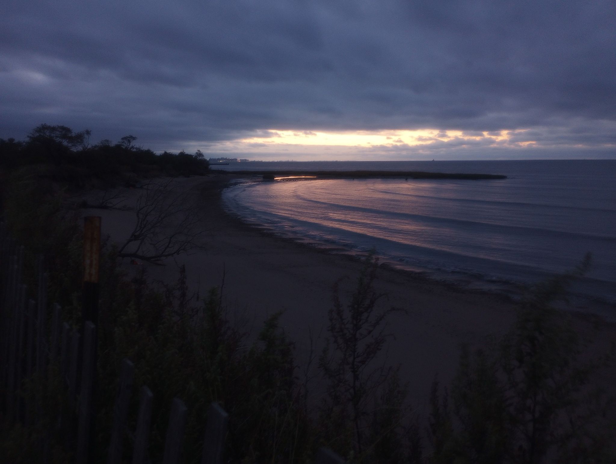 Dark sandy beach and calm ocean at dusk under a cloudy, dramatic sky. - Crookes Point loop from Bay Terrace