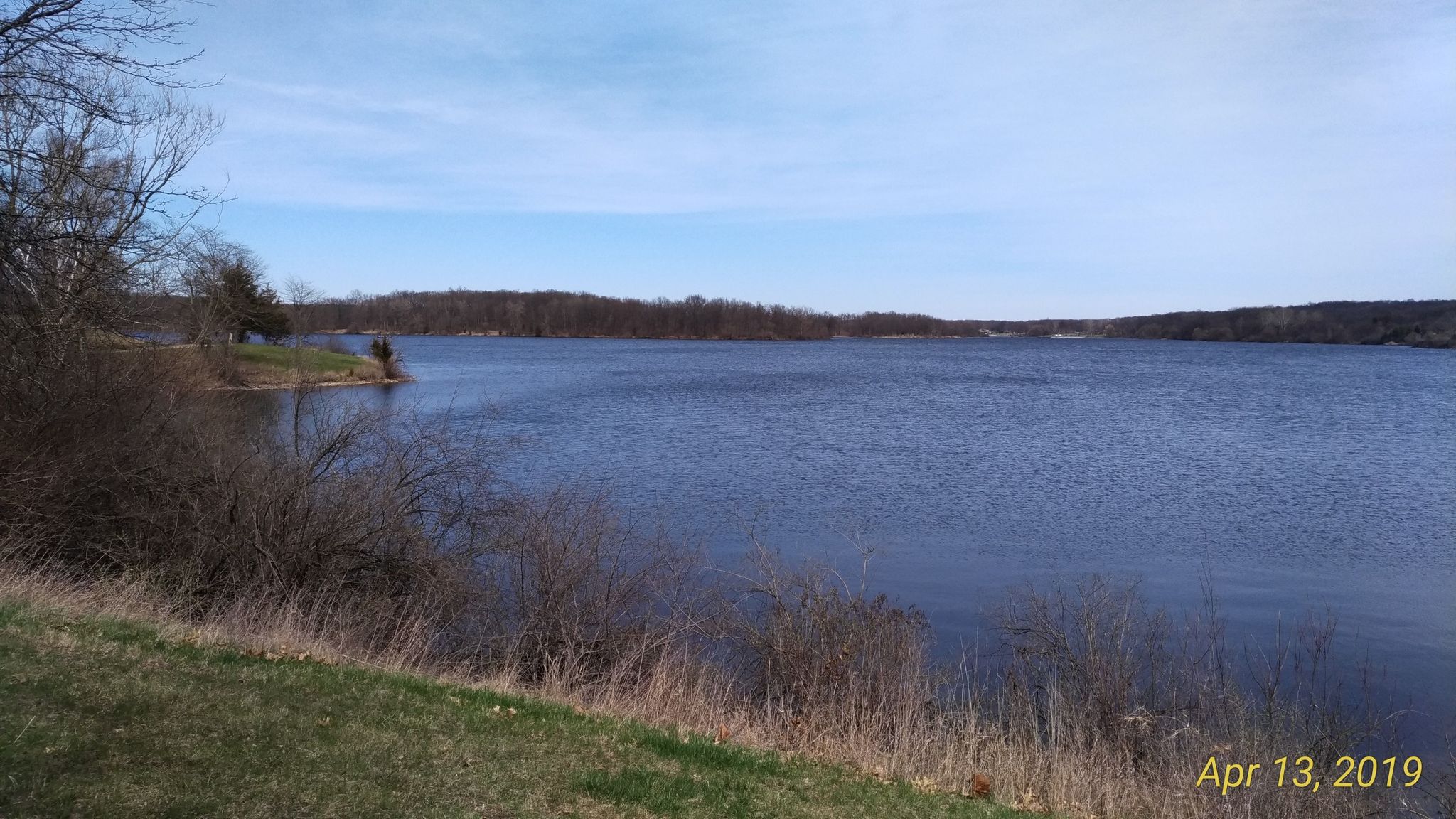 Wide blue lake with distant shorelines and a partly cloudy sky. - Spring Mill Pond – Buno Road bridge loop from Proud Lake State Recreation Area