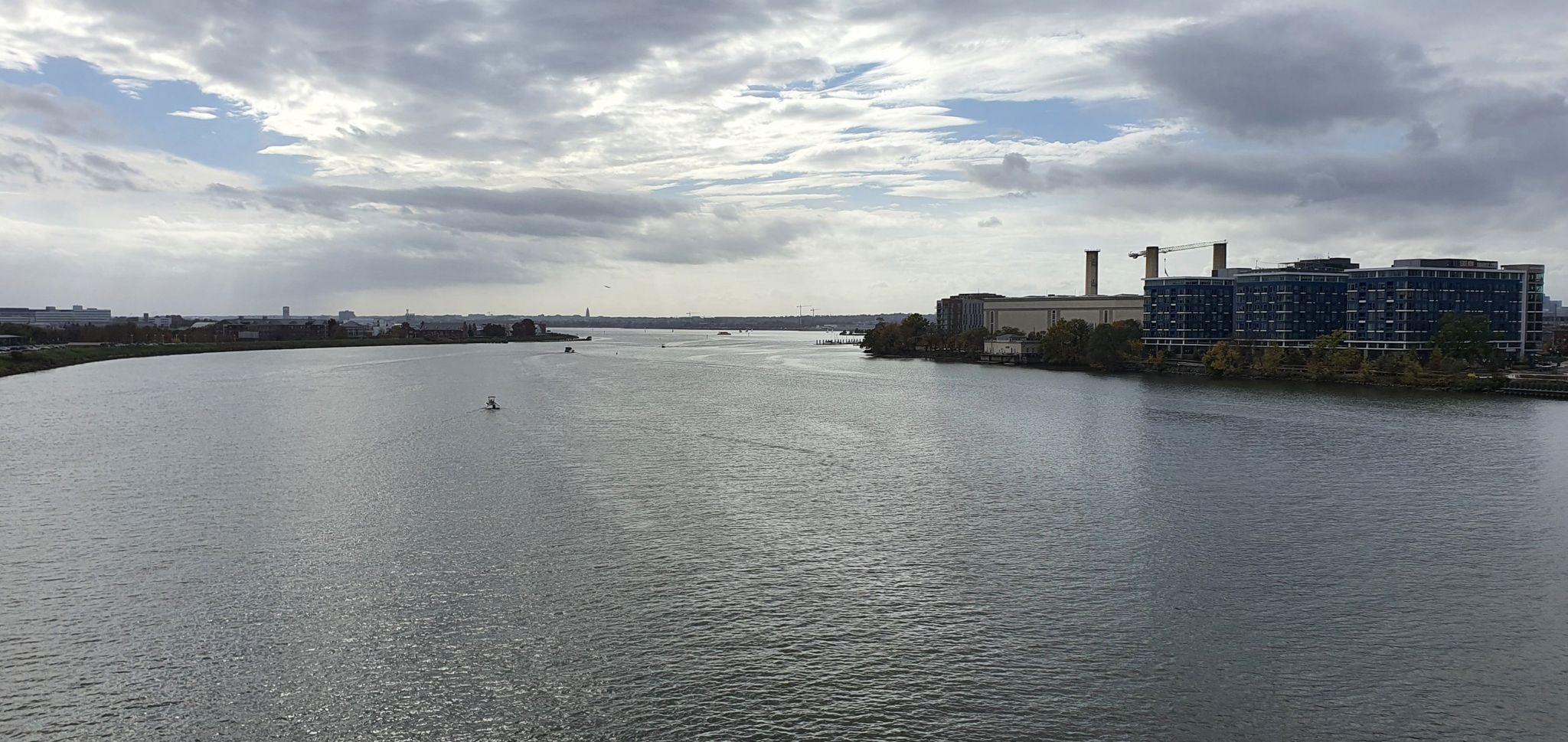 Wide river with distant city buildings and industrial structures under a cloudy sky. - View of Navy Yard loop from Audi Field
