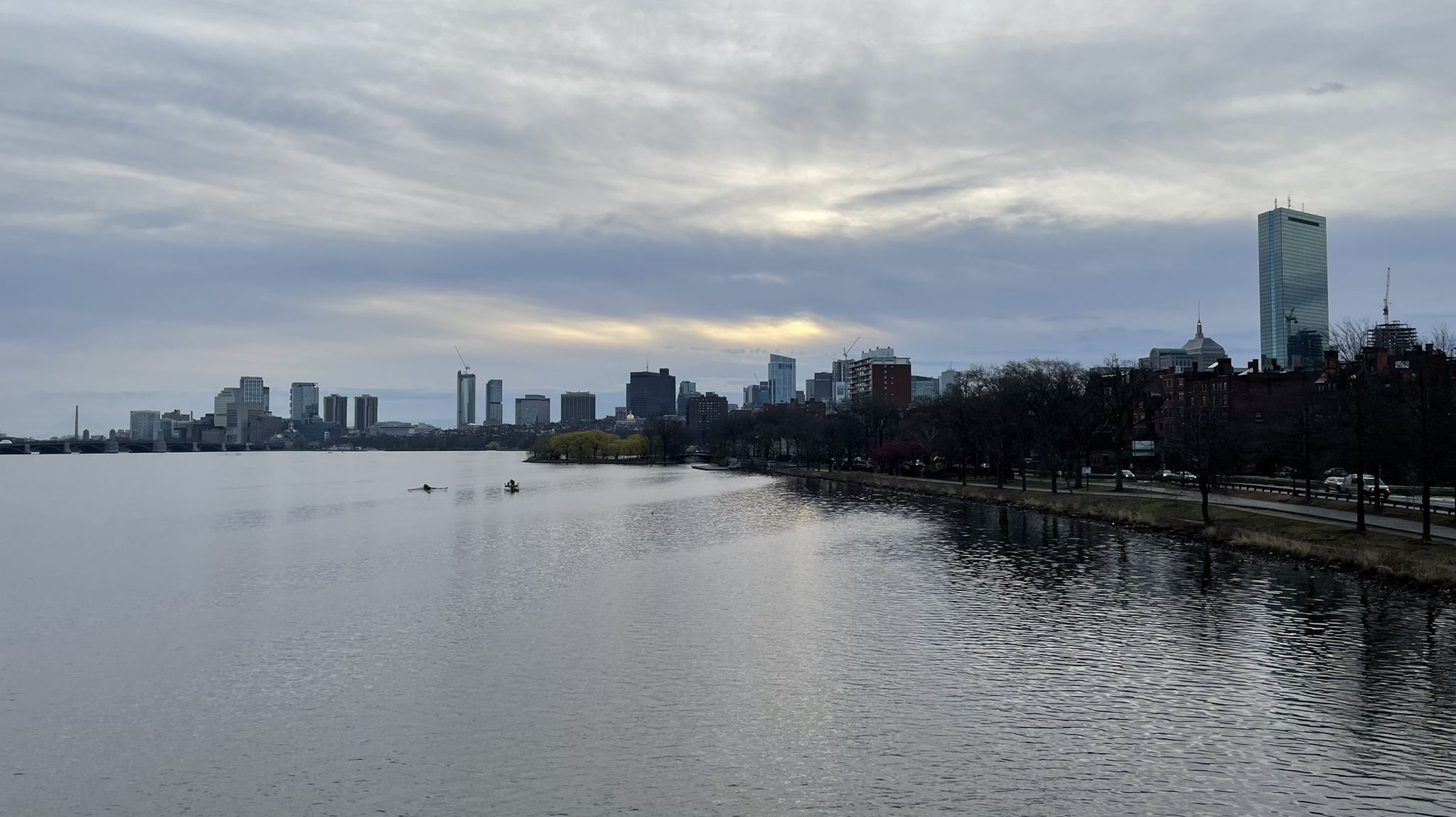 Overcast sky above a city skyline reflected in a wide river. - Arnold Arboretum to Bedford via Minuteman Bikeway
