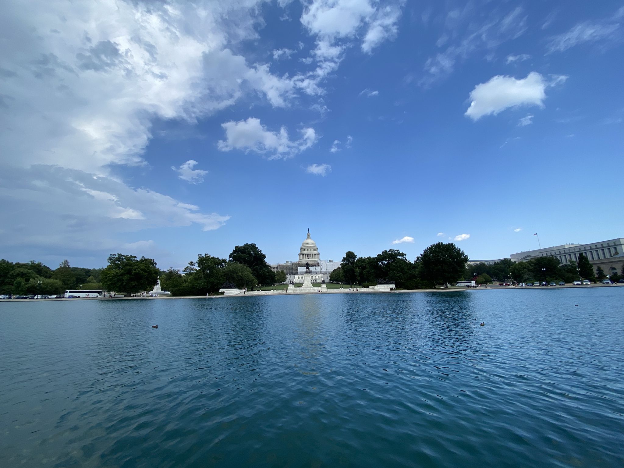 Domed building reflecting in water, green trees, bright blue sky. - Capitol Reflecting Pool – U.S. Capitol loop from United States House of Representatives