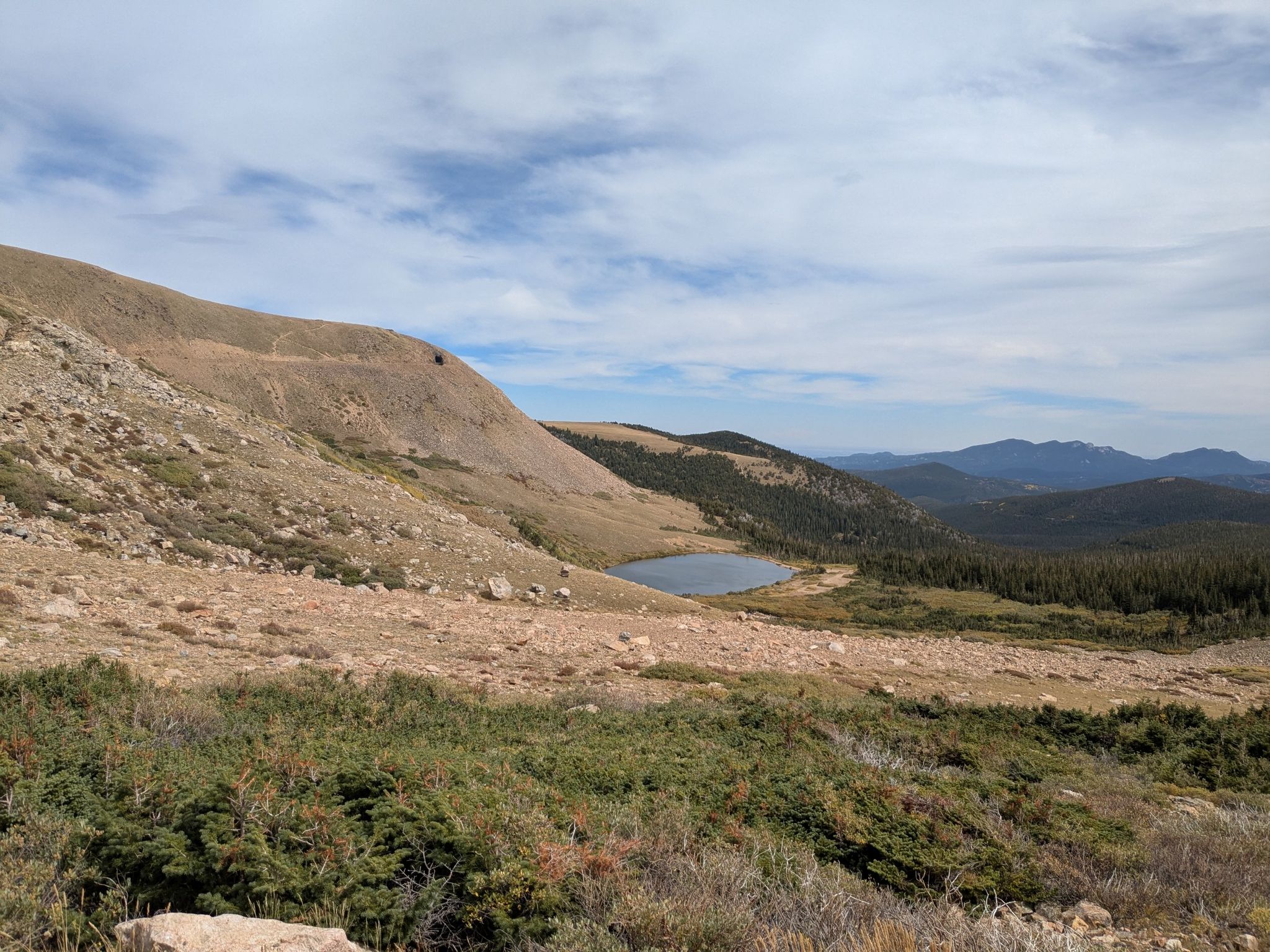 Mountain landscape with a small lake, distant forest, under cloudy sky. - South Boulder Creek, Boulder Wagon, Rollins Pass and Forest Lakes Loop