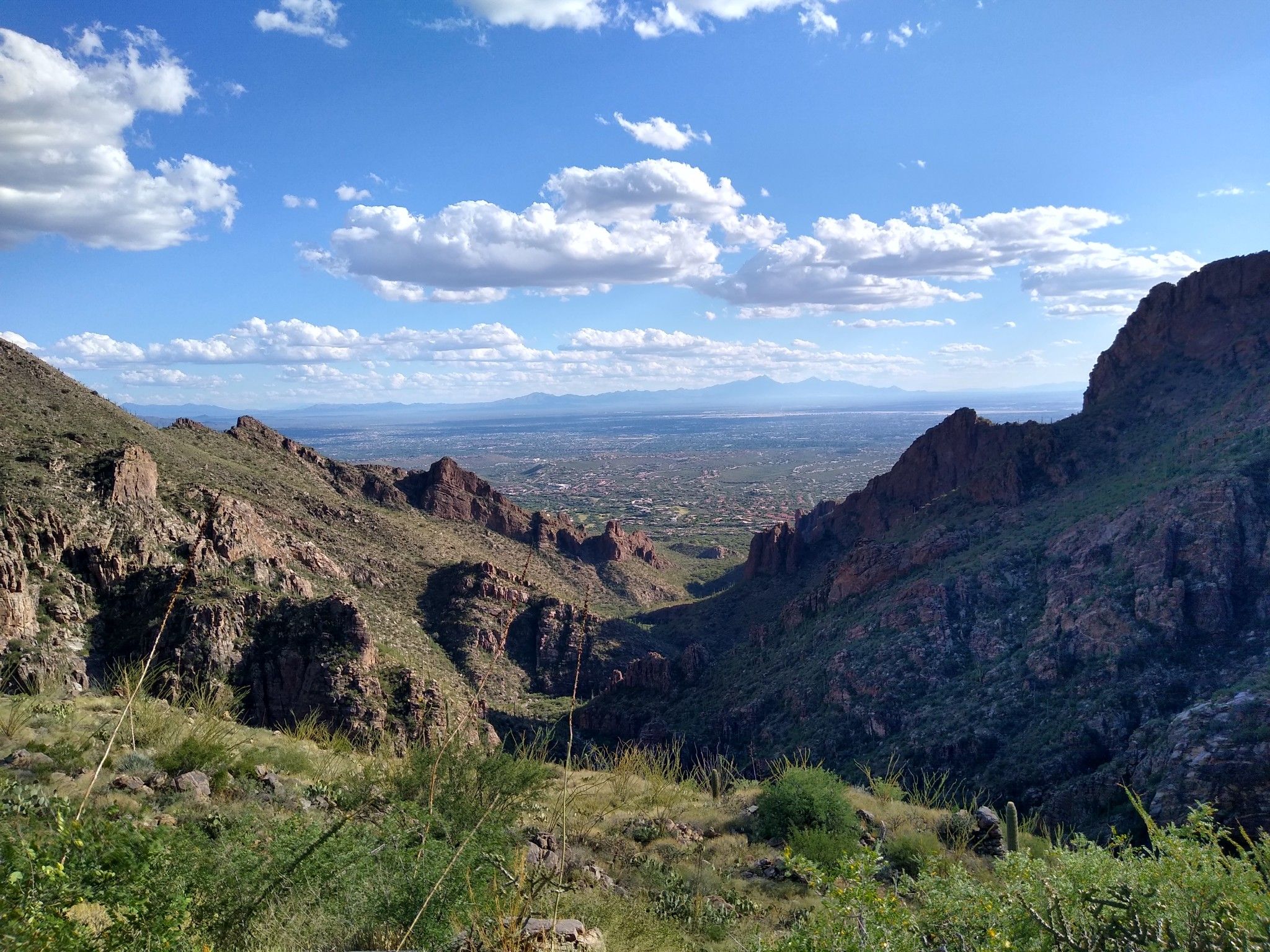 Mountain valley view with distant city under a partly cloudy sky. - Maiden Pools via Ventana Trail