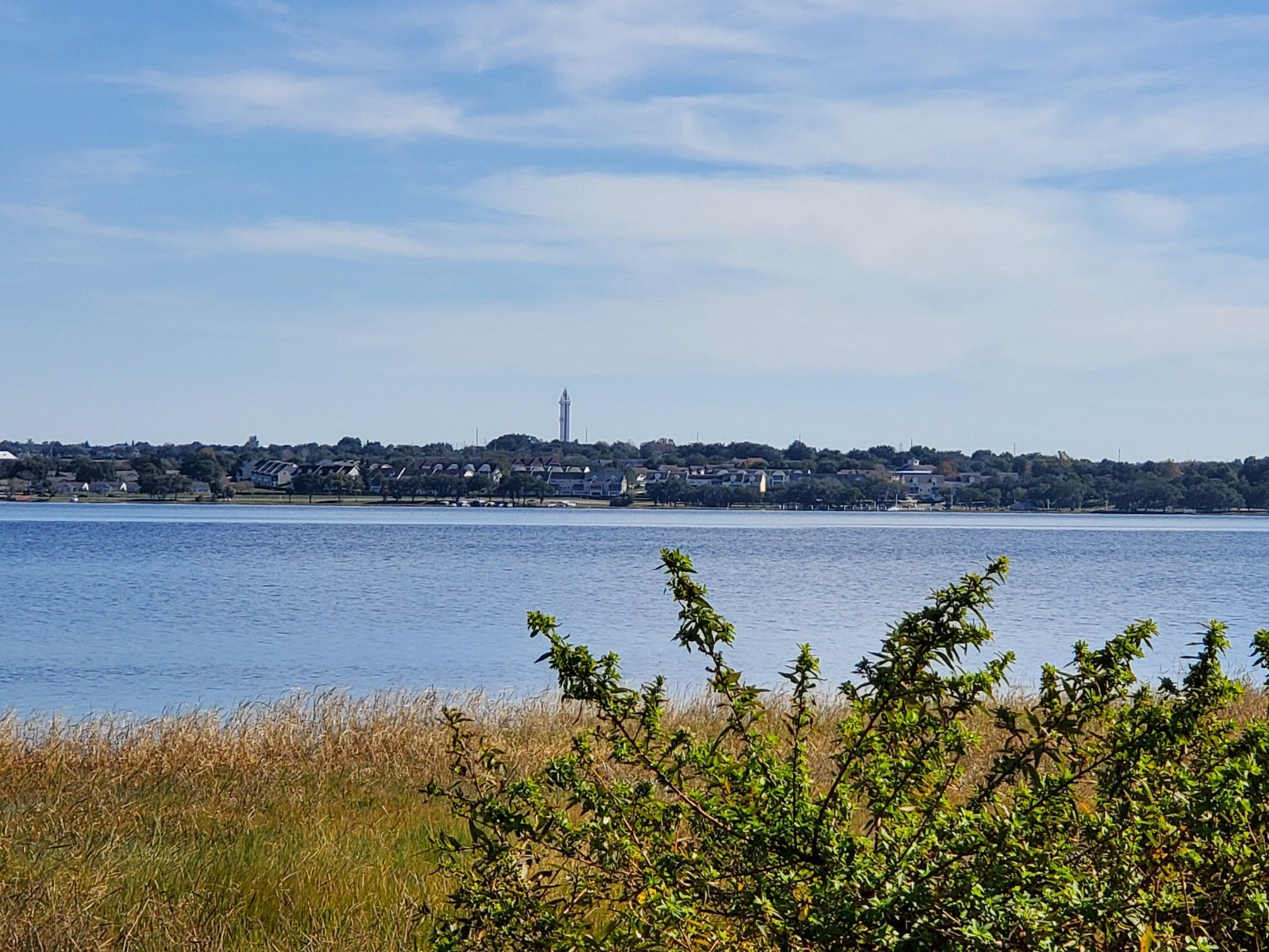 Distant town skyline across a wide lake under a bright blue sky. - South Lake Trail