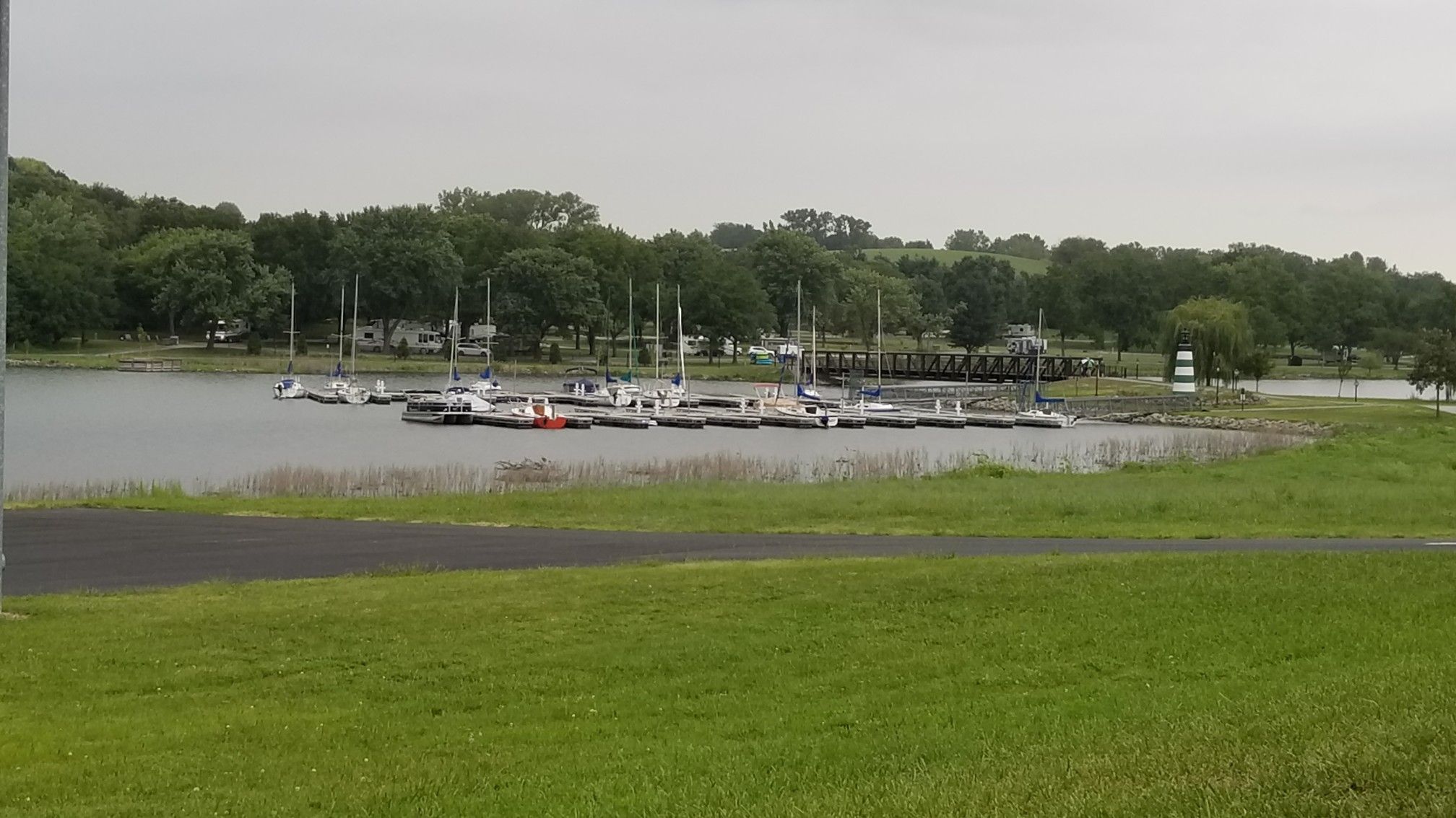 Marina with sailboats on calm water, surrounded by green grass and trees. - Keystone Trail – Cunningham Lake Bridge loop from Benson High School