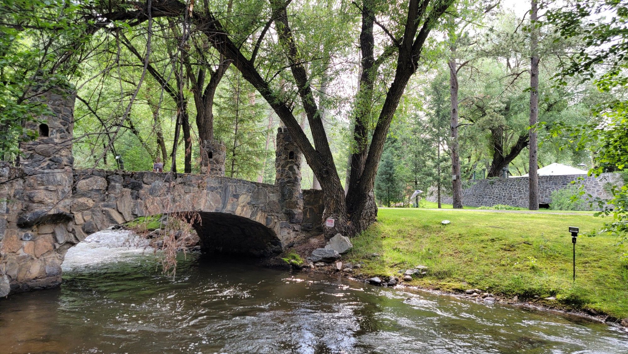 Stone bridge over a calm river, surrounded by lush green trees. - Bruin Bluff Trail Loop