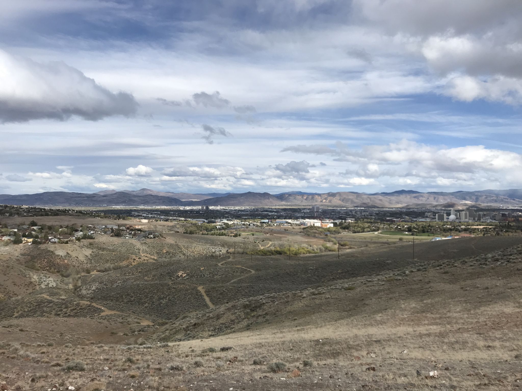Expansive view of dry hills overlooking a distant city under cloudy skies. - Peavine Halo and Poedunk Loop