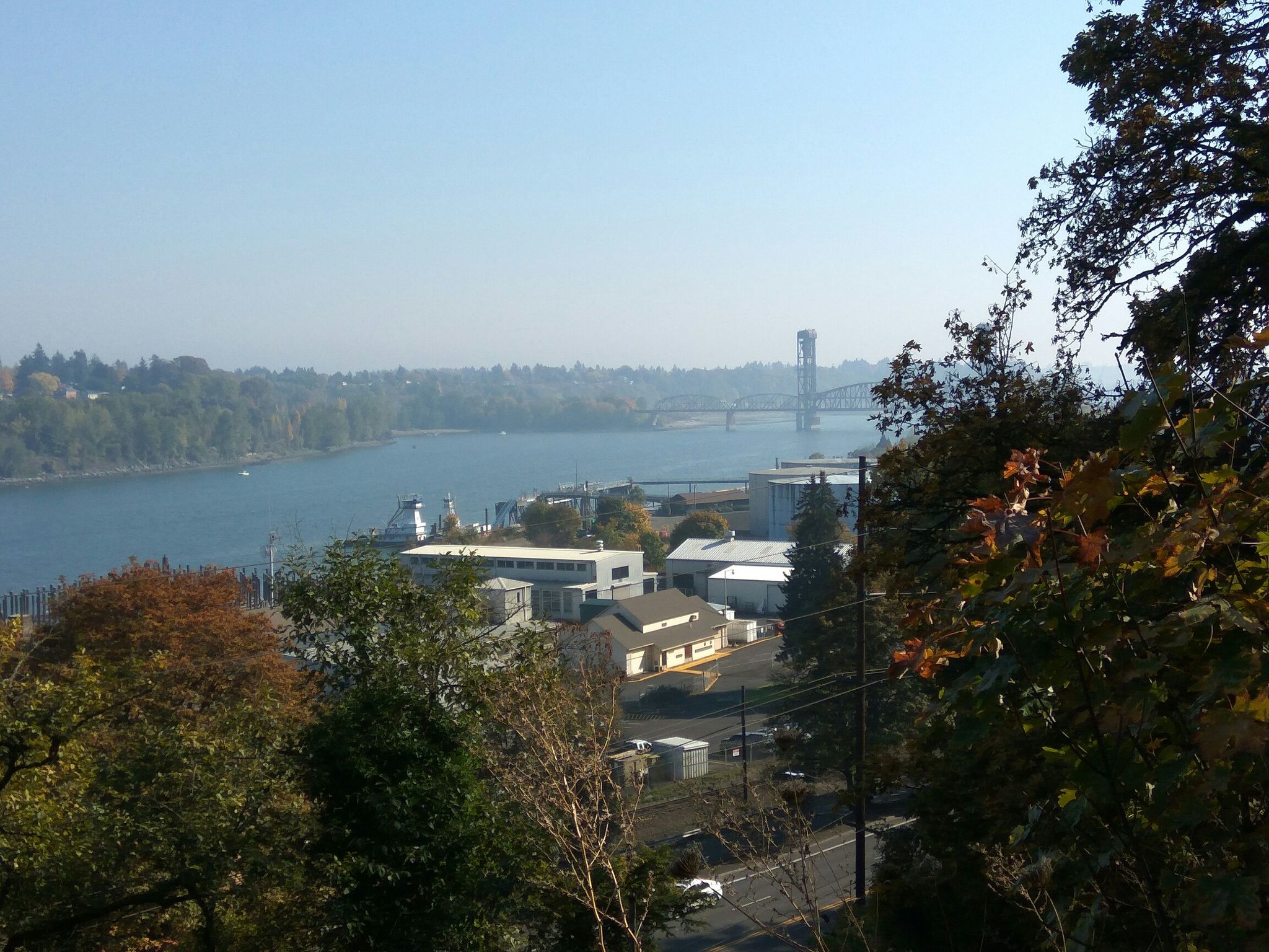 Wide river, distant bridge, and waterfront buildings under a clear sky. - Ridge Trail and Hardesty Trail – Forest Park
