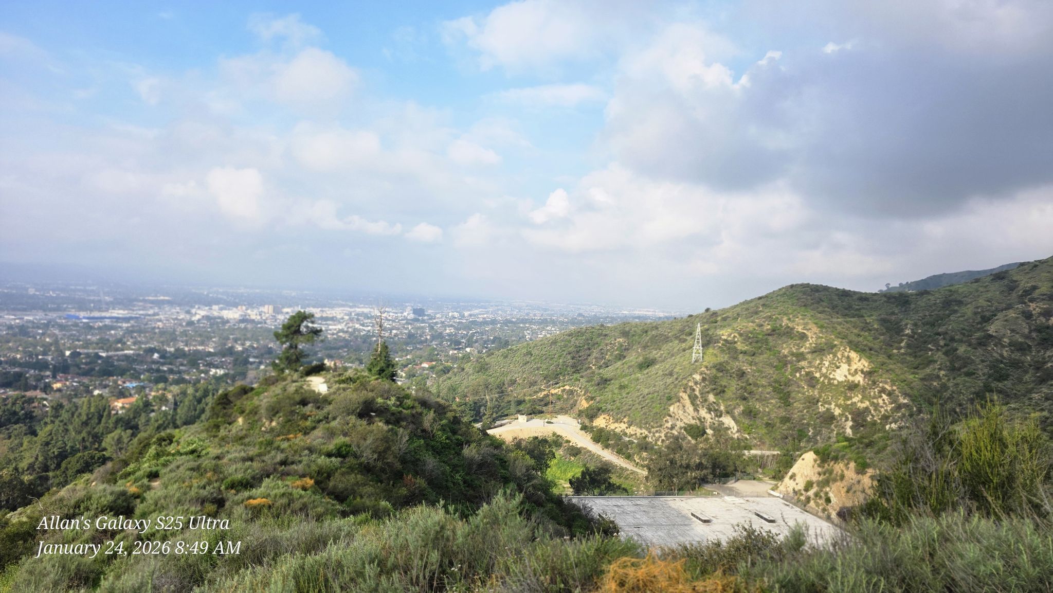 Green hills overlook a distant city under a partly cloudy sky. - Brand Park loop