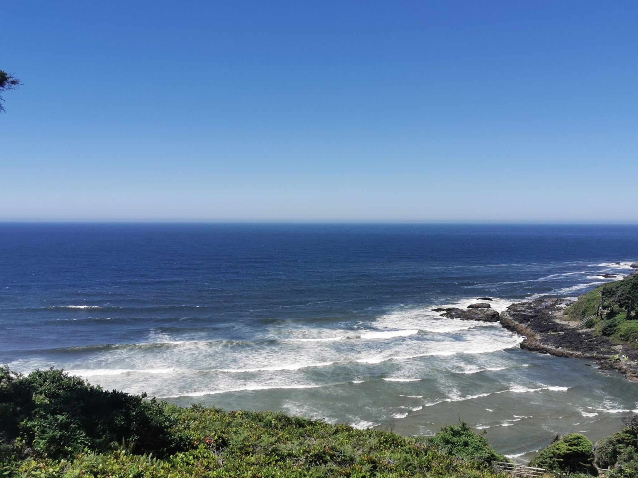 Bright sunny day over a vast blue ocean with a rocky coastline. - Saint Perpetua Trail
