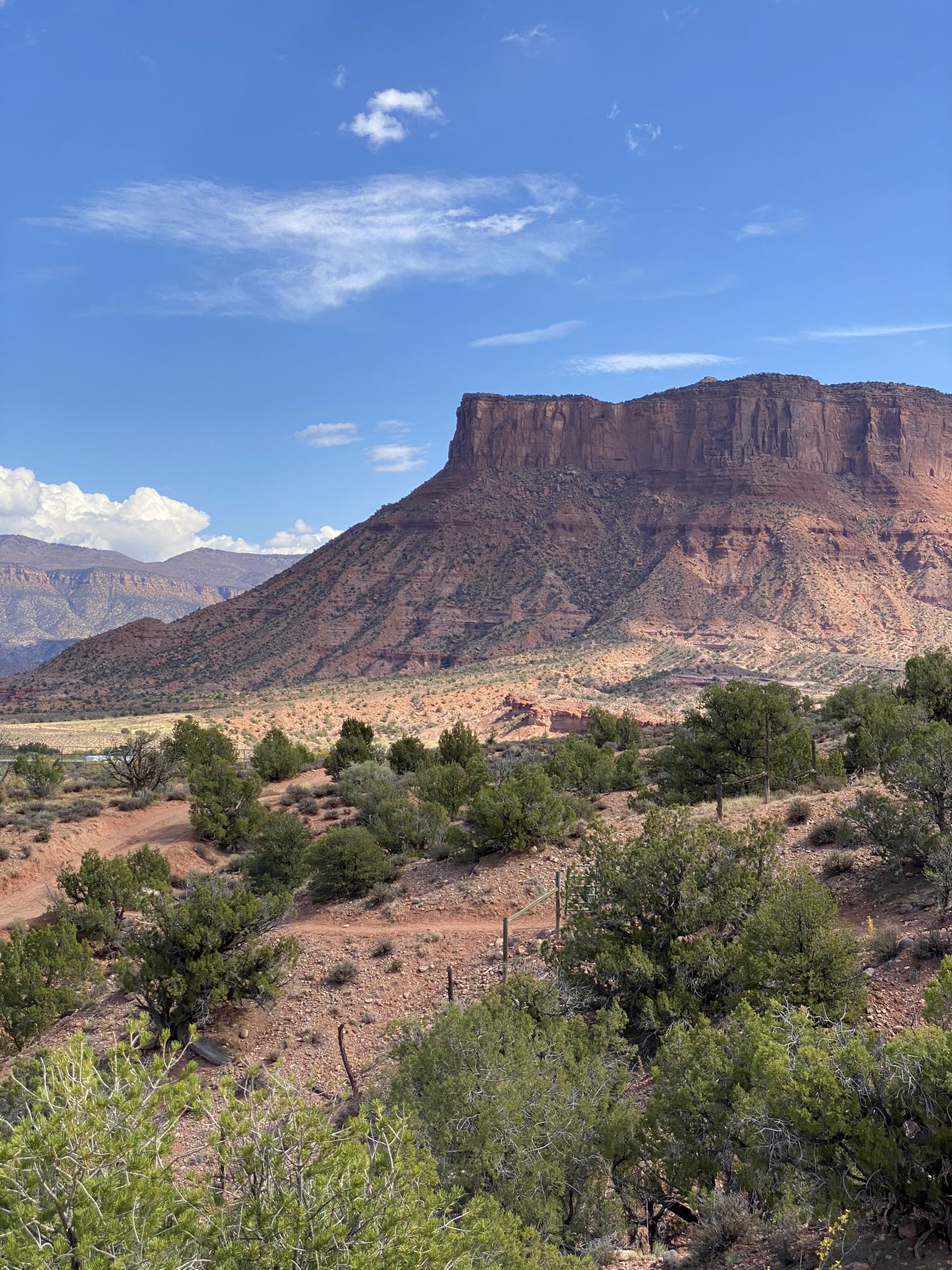 Majestic red mesa dominates a sunny desert landscape with scrub brush. - Entrada, Vista Grande, Lumsden, and Runway Trail Loop
