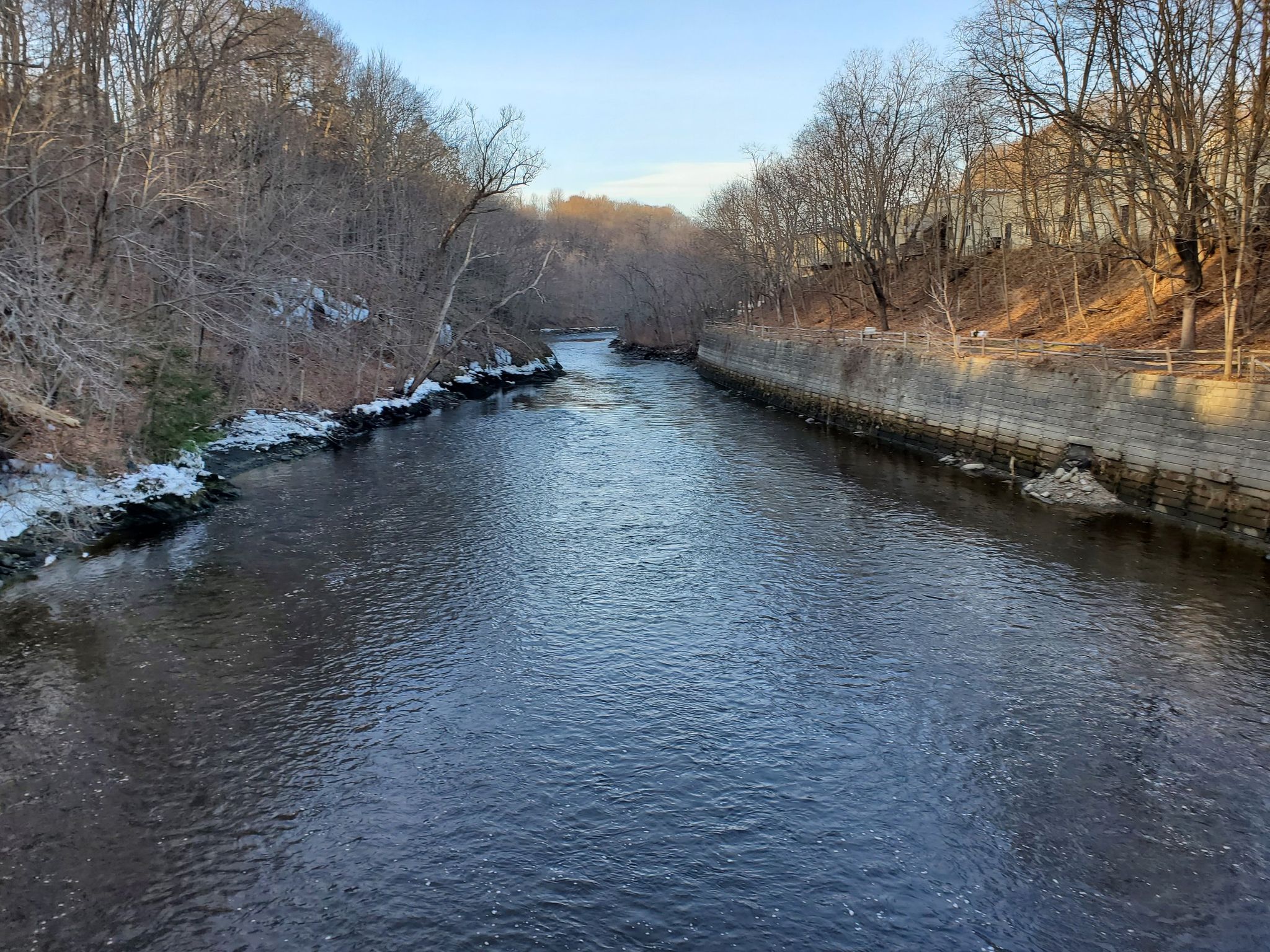 River flowing between wooded banks, some snow, clear sky. - Kenduskeag Stream Trail