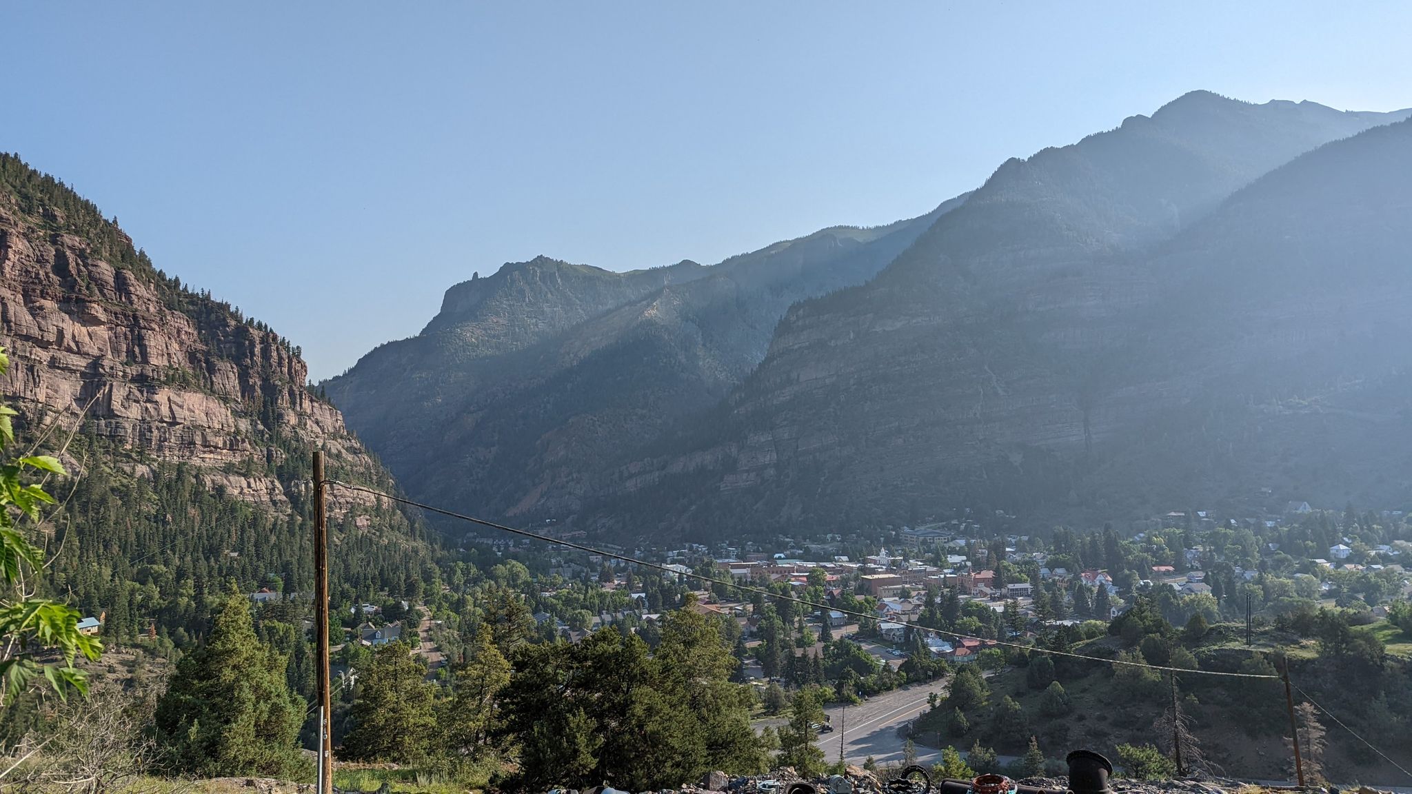 A town nestled in a mountain valley under a clear, hazy sky. - Imogene Pass Road