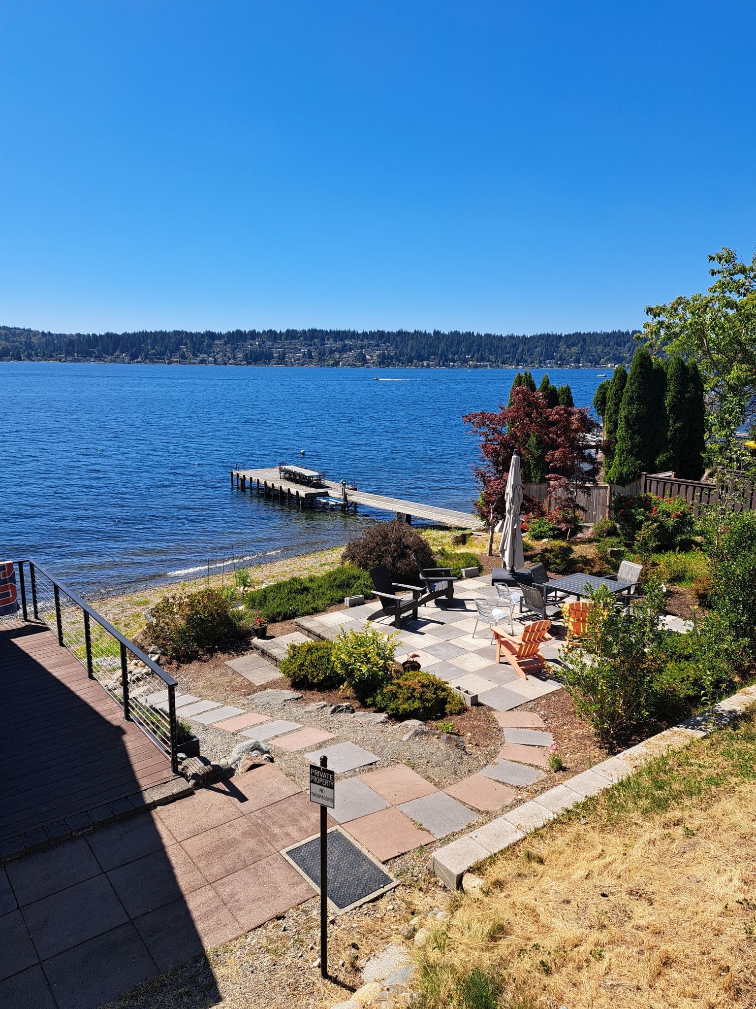 Sunny lakeside patio with a dock extending into the clear blue water. - Lake Sammamish loop from Lake Sammamish