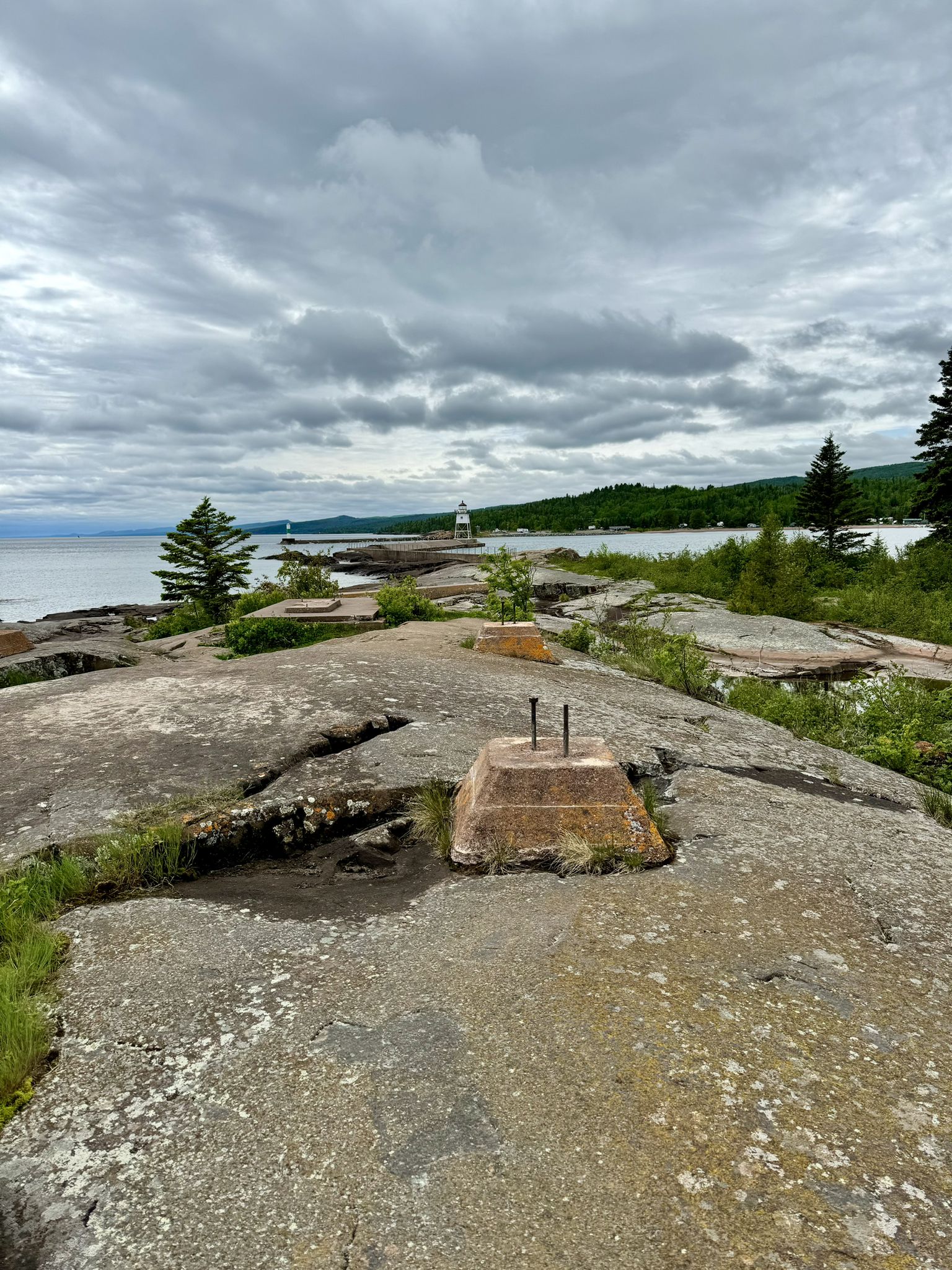 Overcast view of rocky terrain with a concrete base and distant lighthouse. - Artists' Point Trail