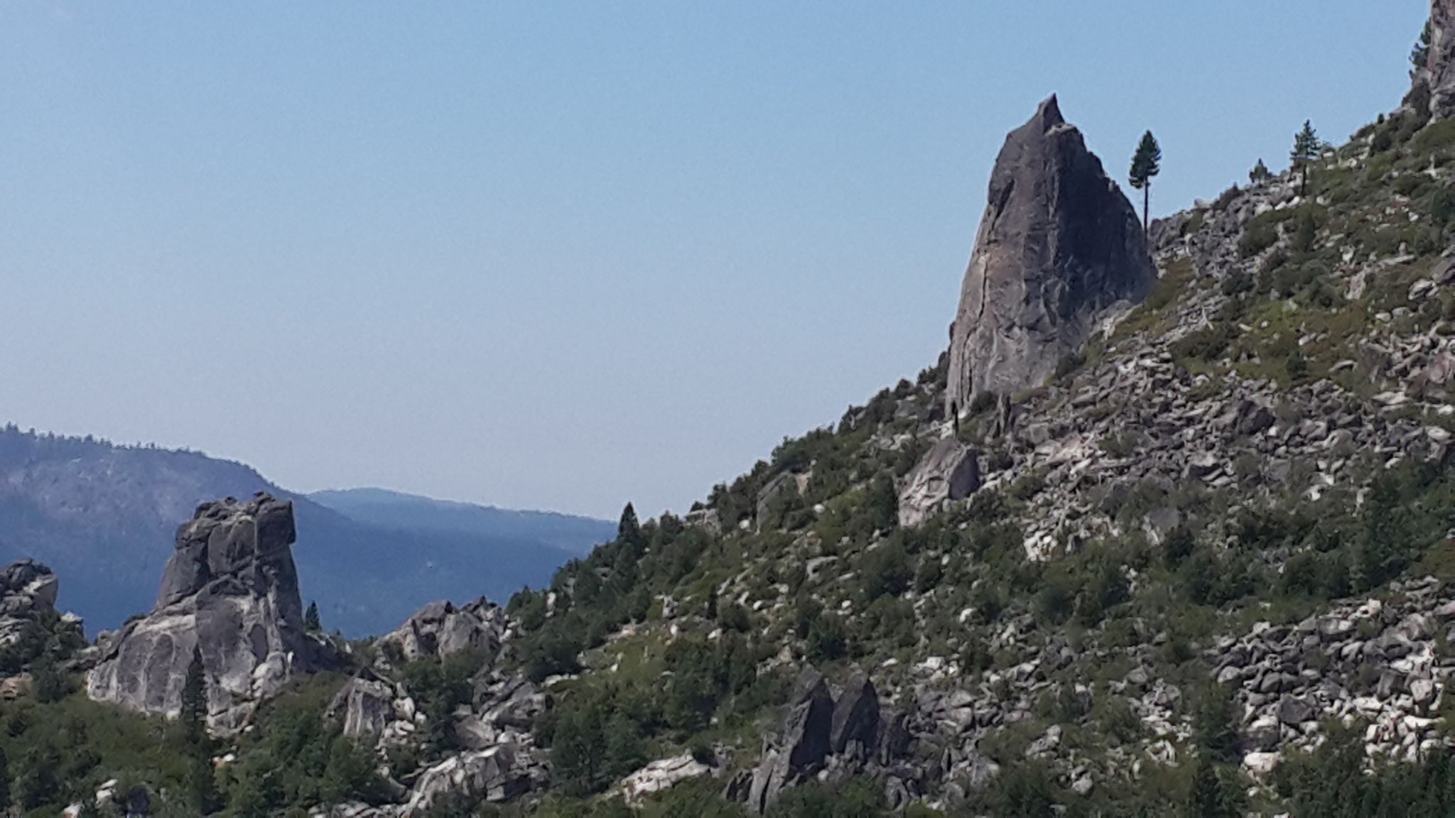 Towering rock formations and sparse trees on a sunny, rocky mountain slope. - Wrights Lake loop