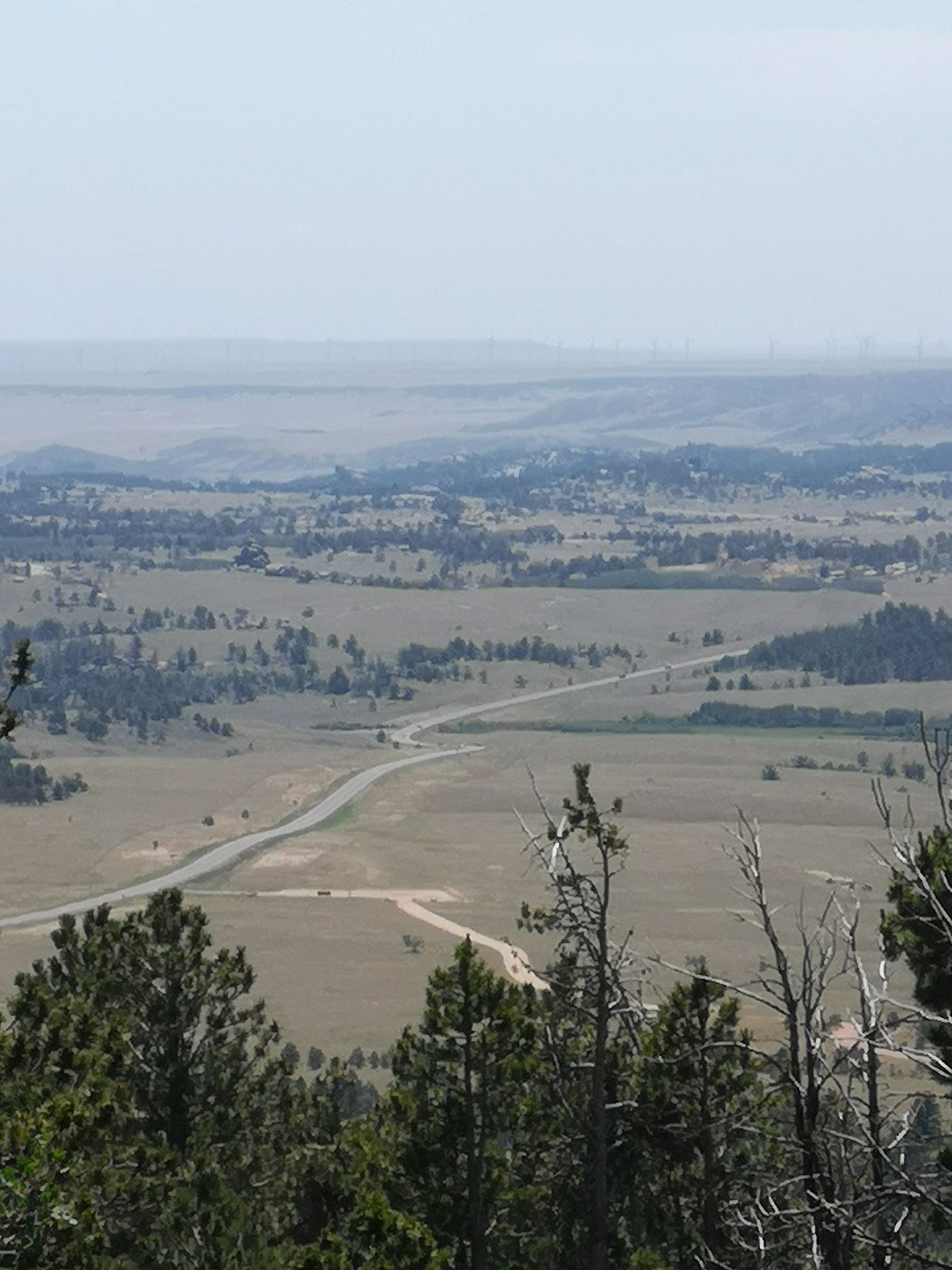 Hazy aerial view of a road winding through plains and scattered trees. - Happy Jack loop
