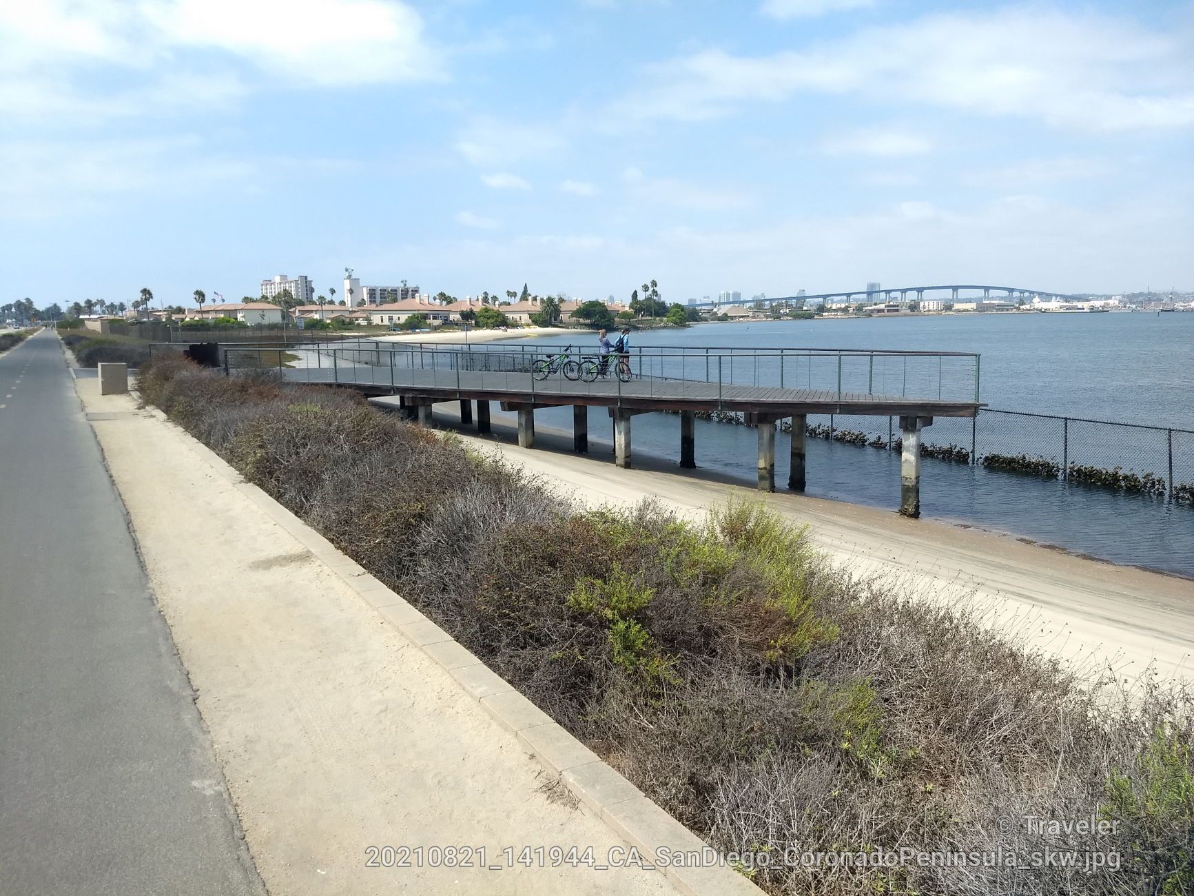 Elevated boardwalk next to a road and water, with a distant bridge. - Glorietta Bay Park – Silver Strand State Beach loop from Coronado Cays
