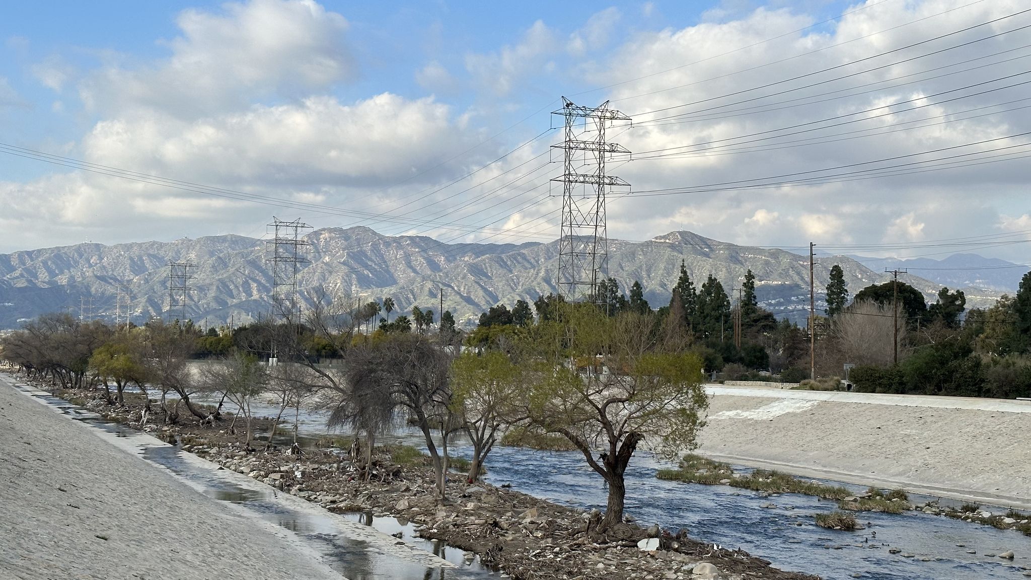 Riverbed with trees and power lines, mountains in the cloudy distance. - Los Angeles River Greenway and Griffith Park Loop