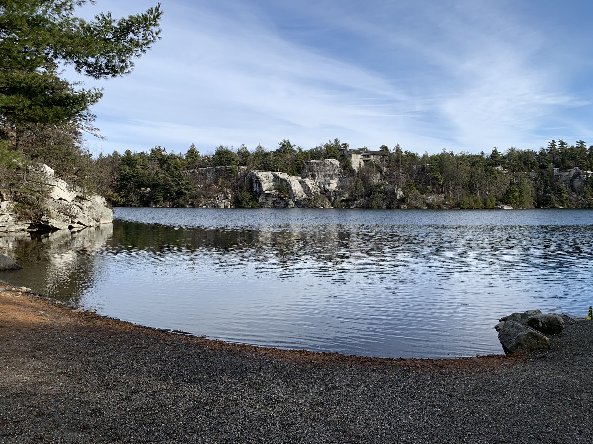 Calm lake surrounded by rocky cliffs and green trees under a bright sky. - Castle Point Carriage Road to Upper Awosting Carriageway Loop