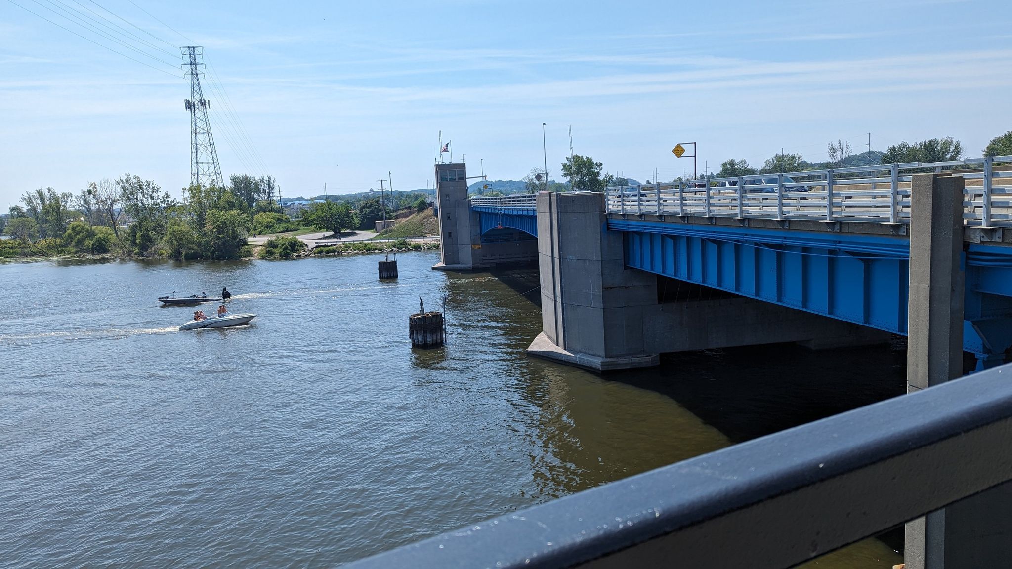 Blue bridge over water with two boats on a sunny day. - Fishing Dock at Pomona Park – Petty's Bayou Bridge loop from Grand Haven
