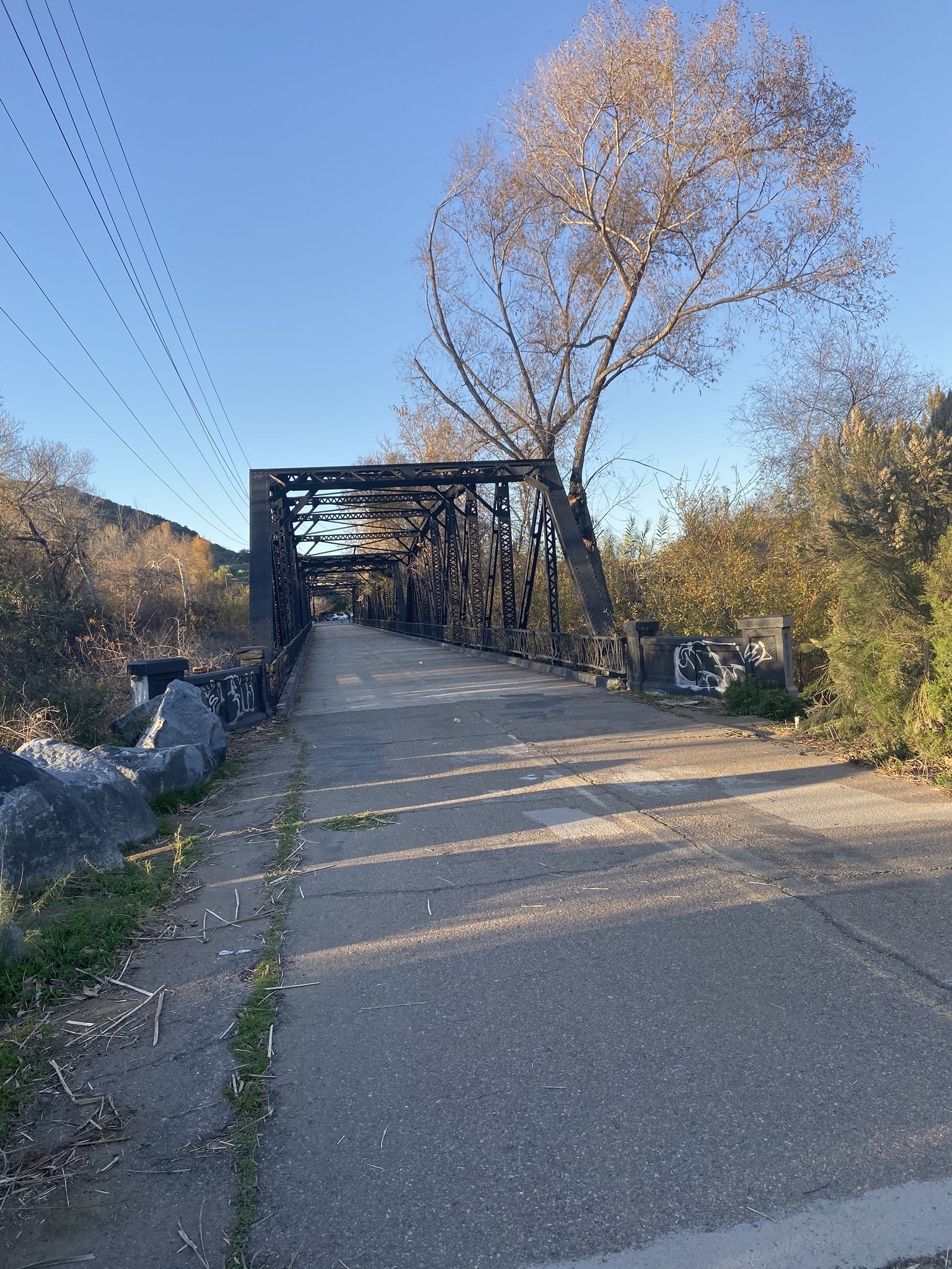 A long, black metal truss bridge with a paved path under a clear sky. - Proctor Valley Road loop from Spring Valley