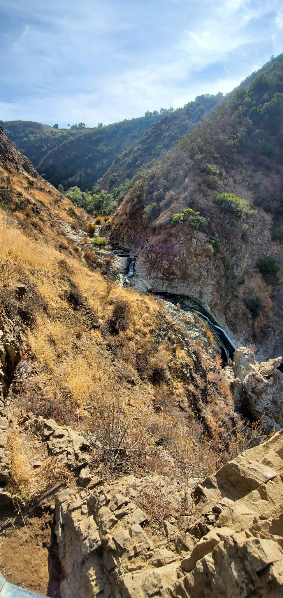 A deep, dry canyon with a winding stream and small waterfall. - Wooden Bridge Over Stream – Paradise Falls loop from Wildwood Park