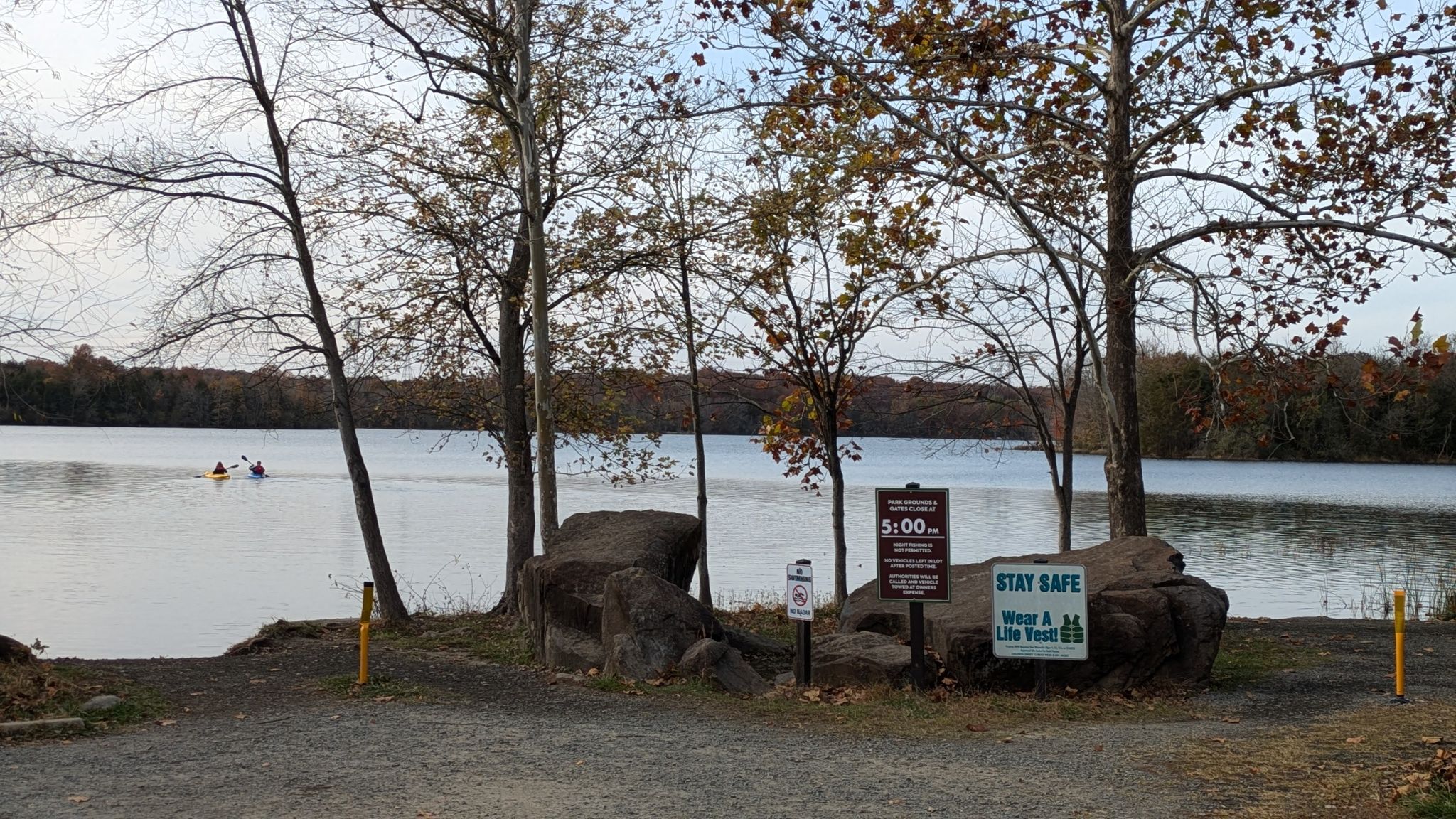 Lake view with two kayakers, signs, and trees under an overcast sky. - Beaverdam Reservoir Trail loop from Broadlands protected nature reserve