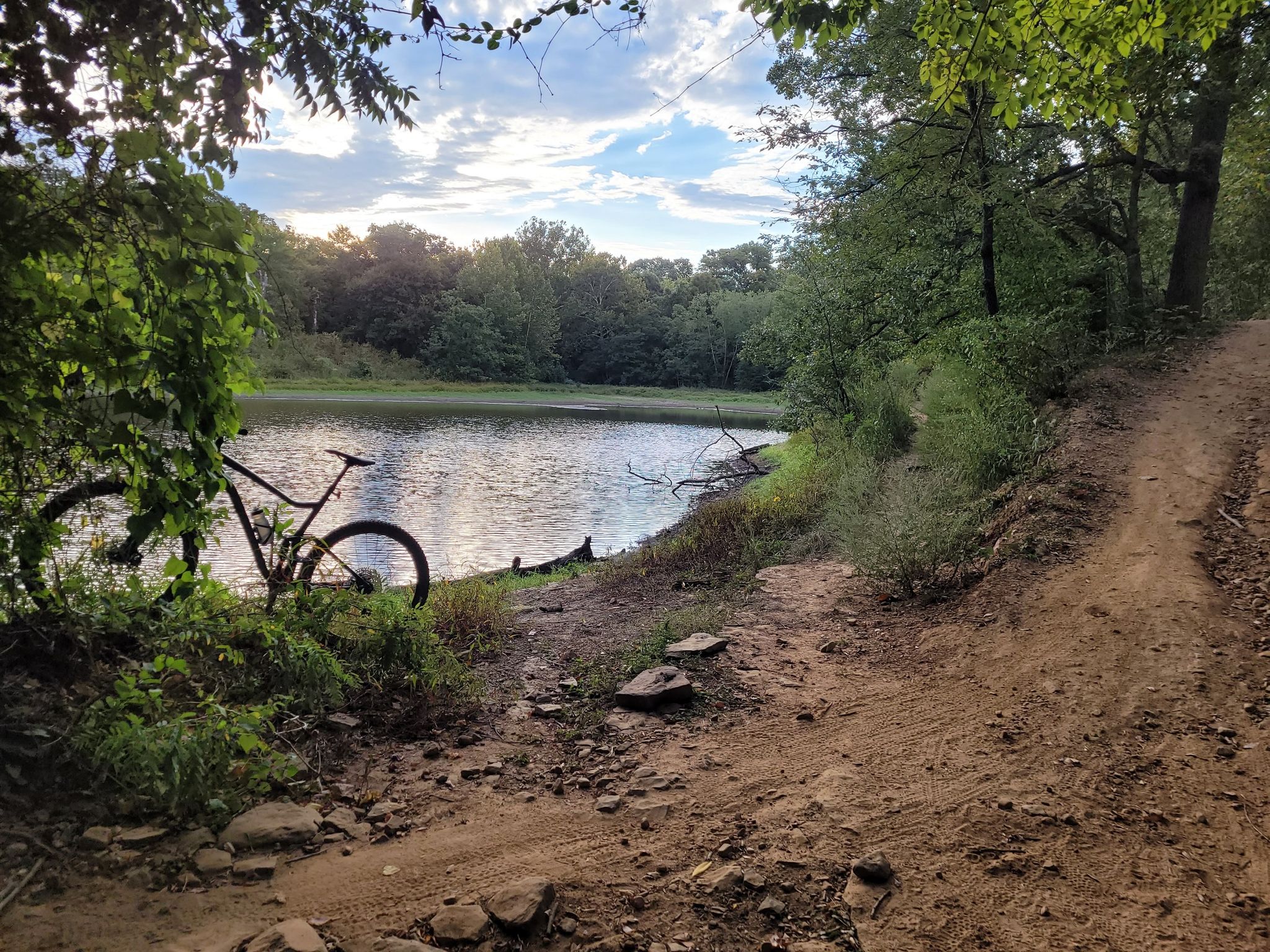 Mountain bike parked by a calm lake with a dirt path under an overcast sky. - Turkey Mountain – Pepsi Lake loop from Turkey Mountain - Lower Lot