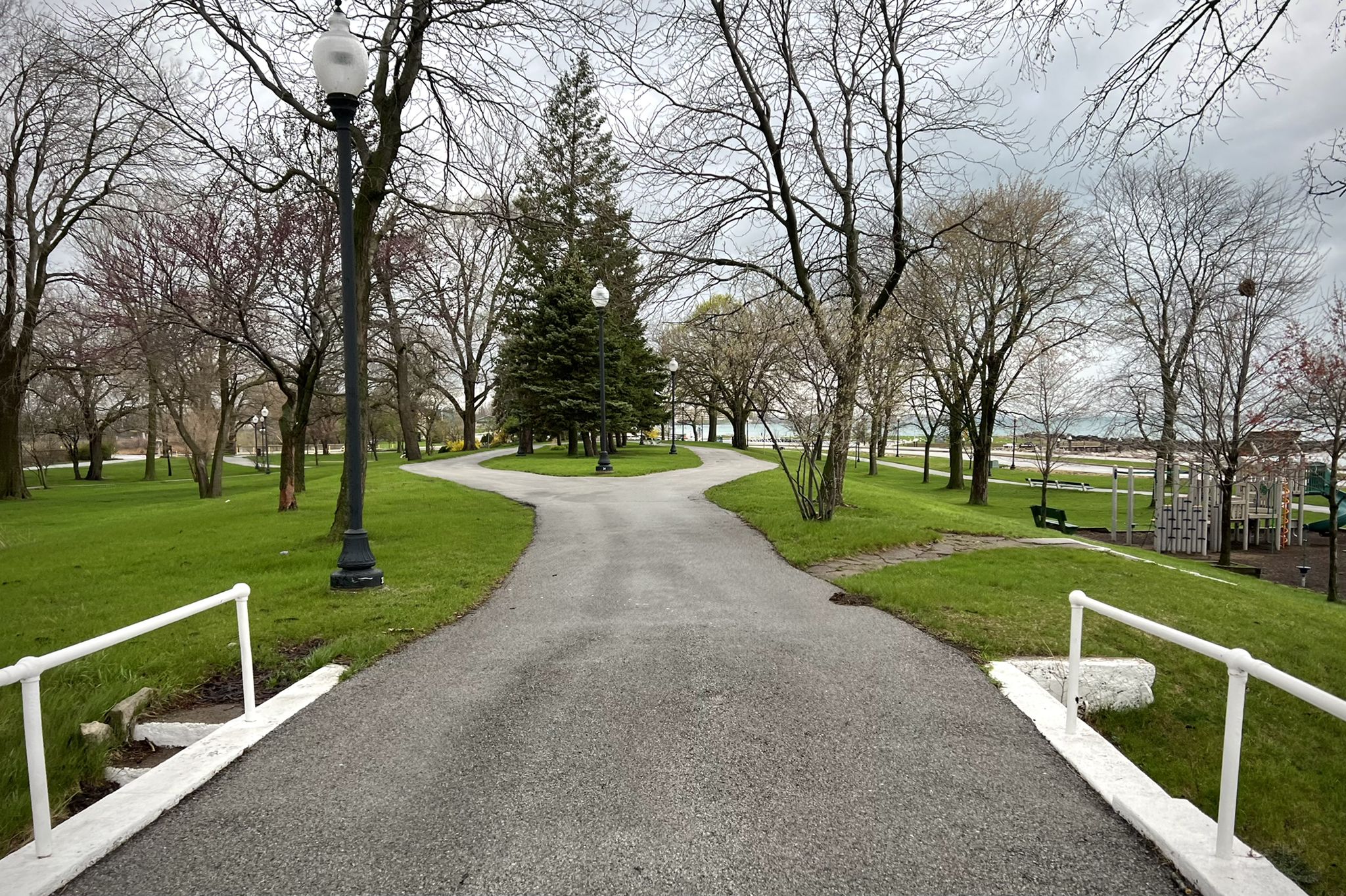 A paved path splits in a park with bare trees under an overcast sky. - The Marquette Greenway