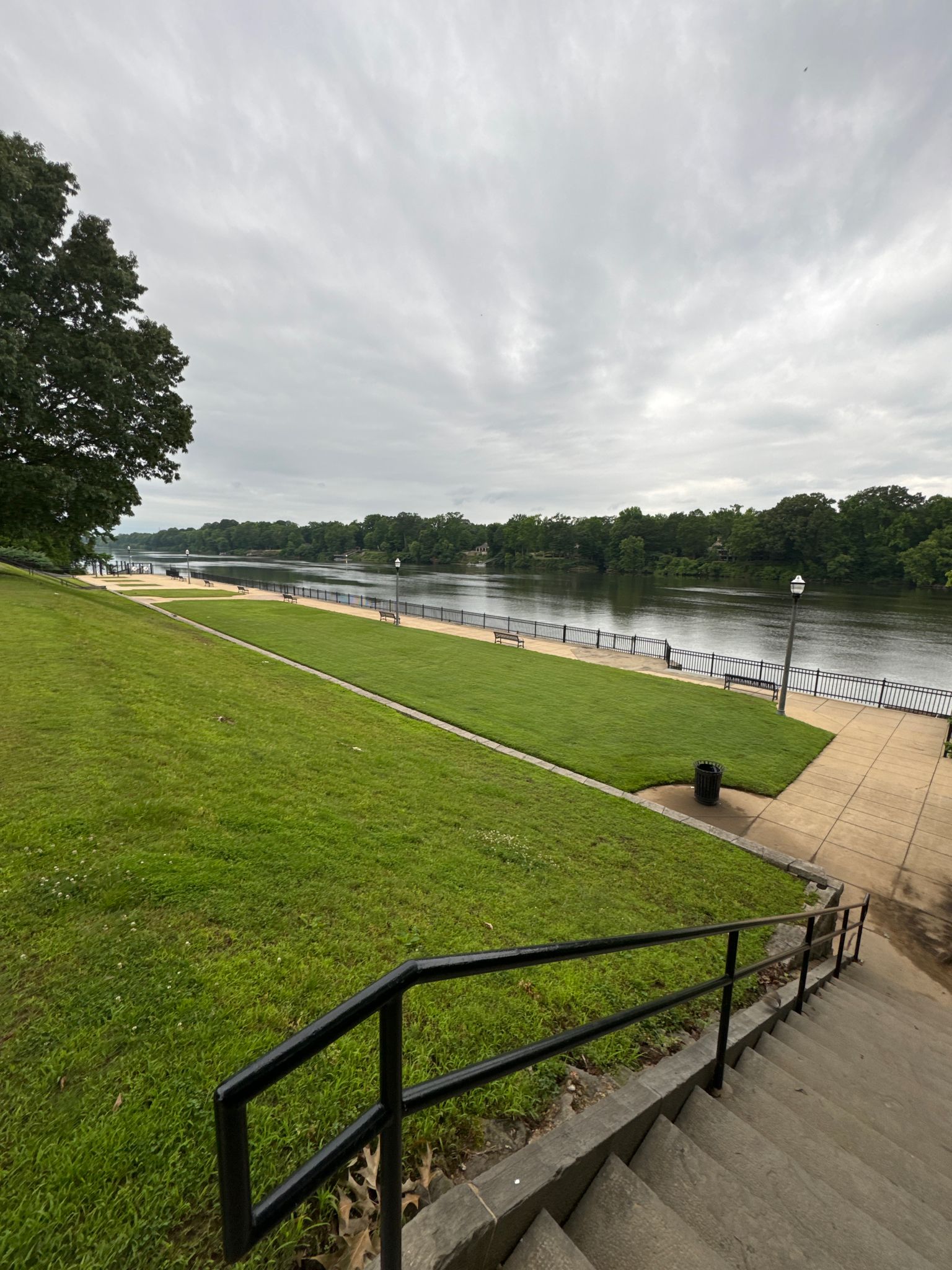 Overcast view of a wide river, green lawn, and concrete stairs. - Tuscaloosa Riverwalk loop from Tuscaloosa